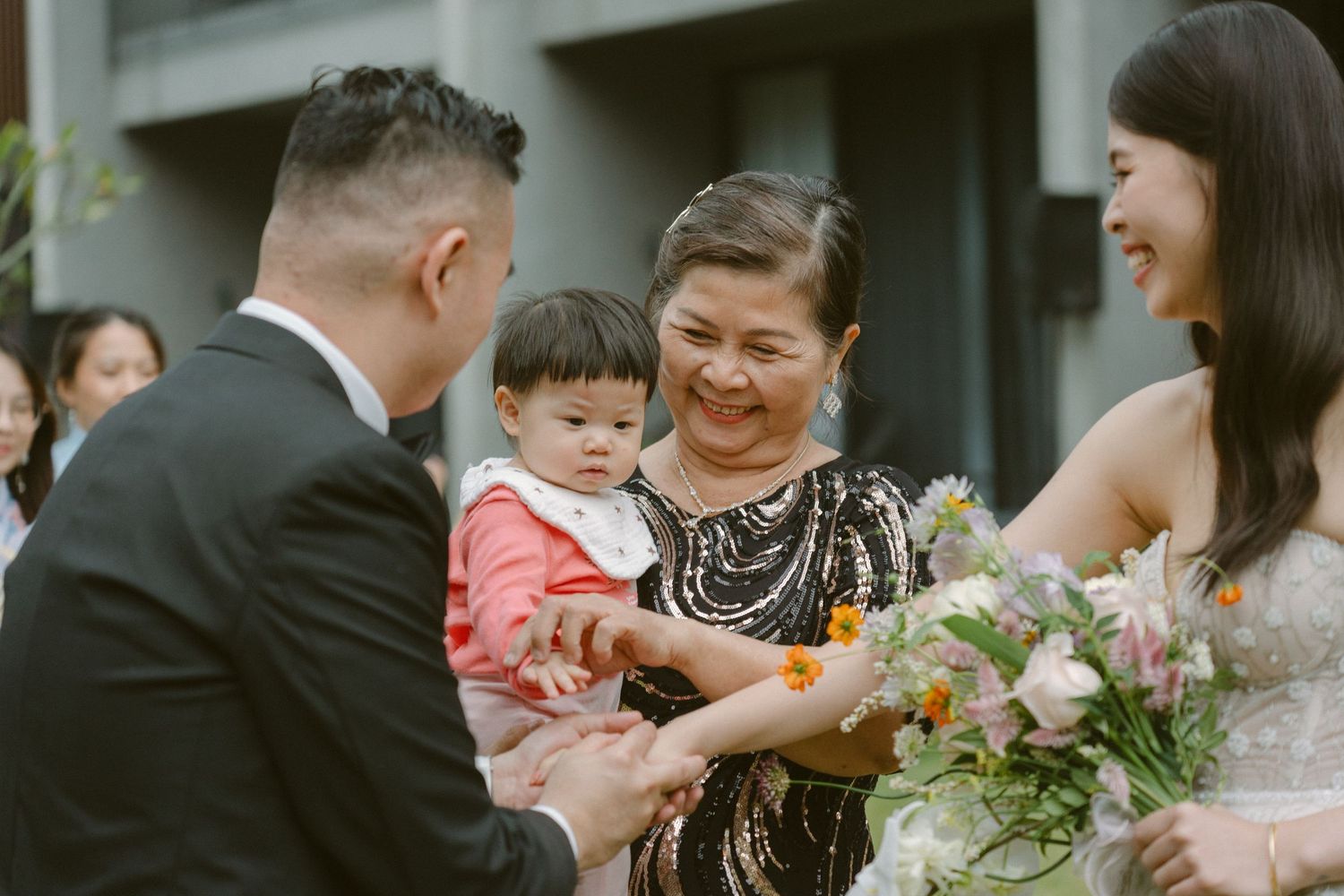 A couple sharing a joyful moment with wedding guests outdoors during a celebratory gathering.