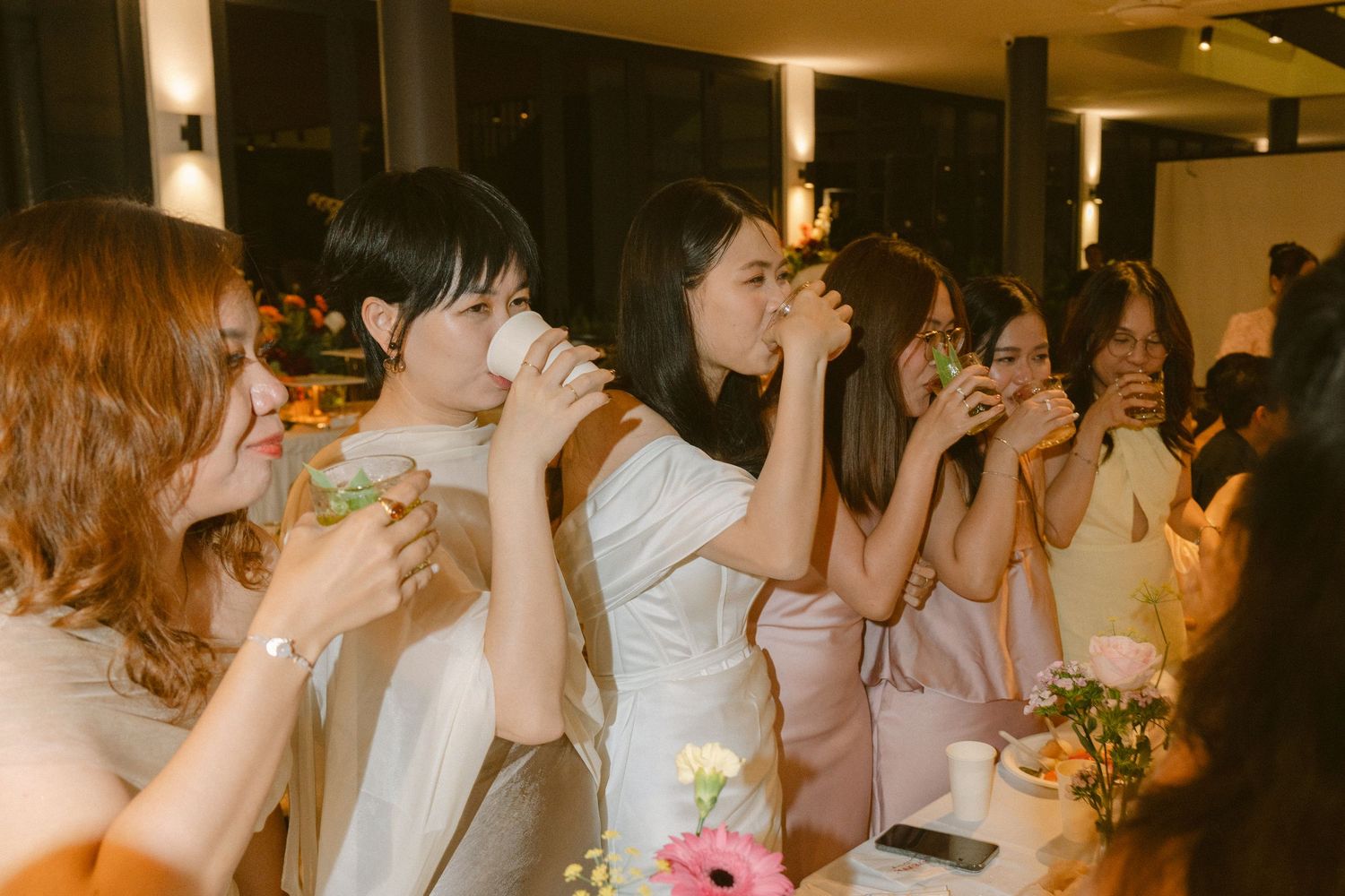 A candid collage of guests at a wedding reception toasting and drinking beverages during celebration.