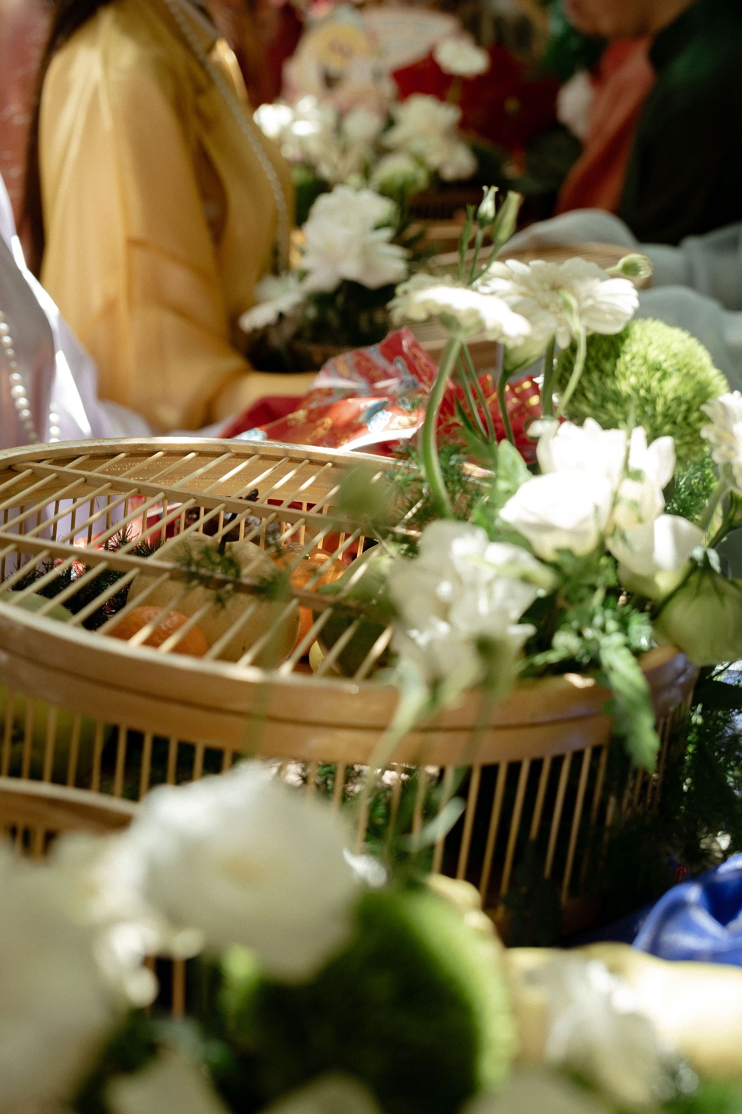 A decorative bird cage adorned with white flowers and greenery arranged for a wedding celebration.