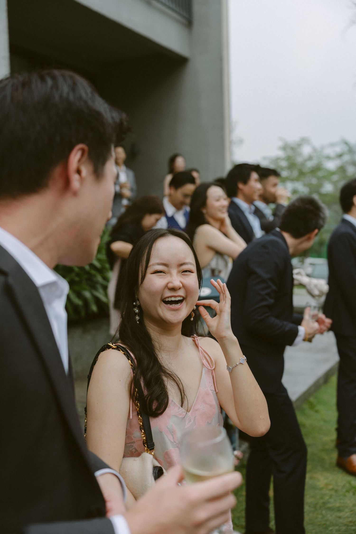 People laughing and socializing at an outdoor wedding reception with glasses of champagne.
