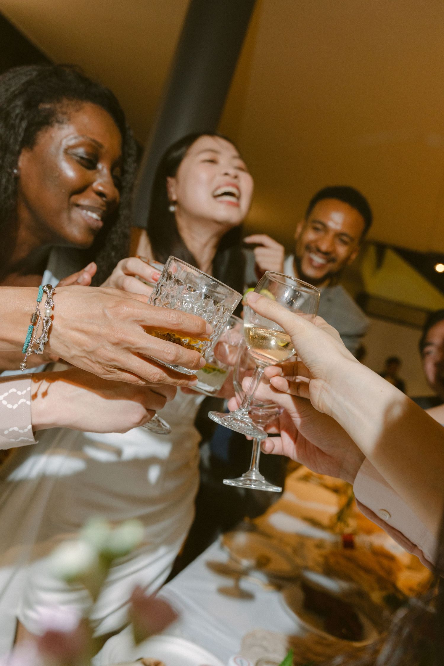 A group of friends raise their glasses together in celebration at a dinner party gathering.