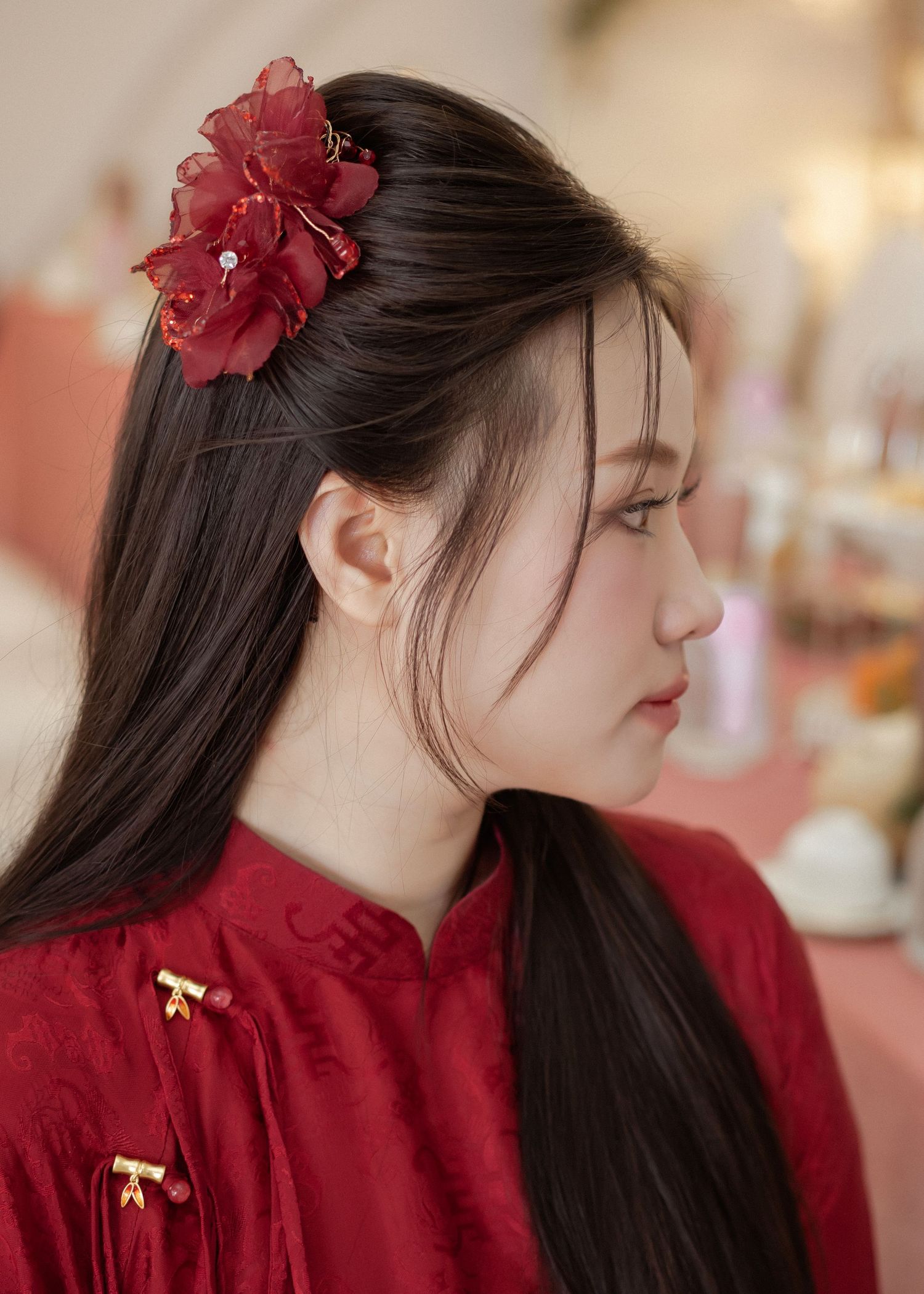 Asian style profile portrait with long dark hair, red flower hairpiece and traditional red mandarin collar dress.