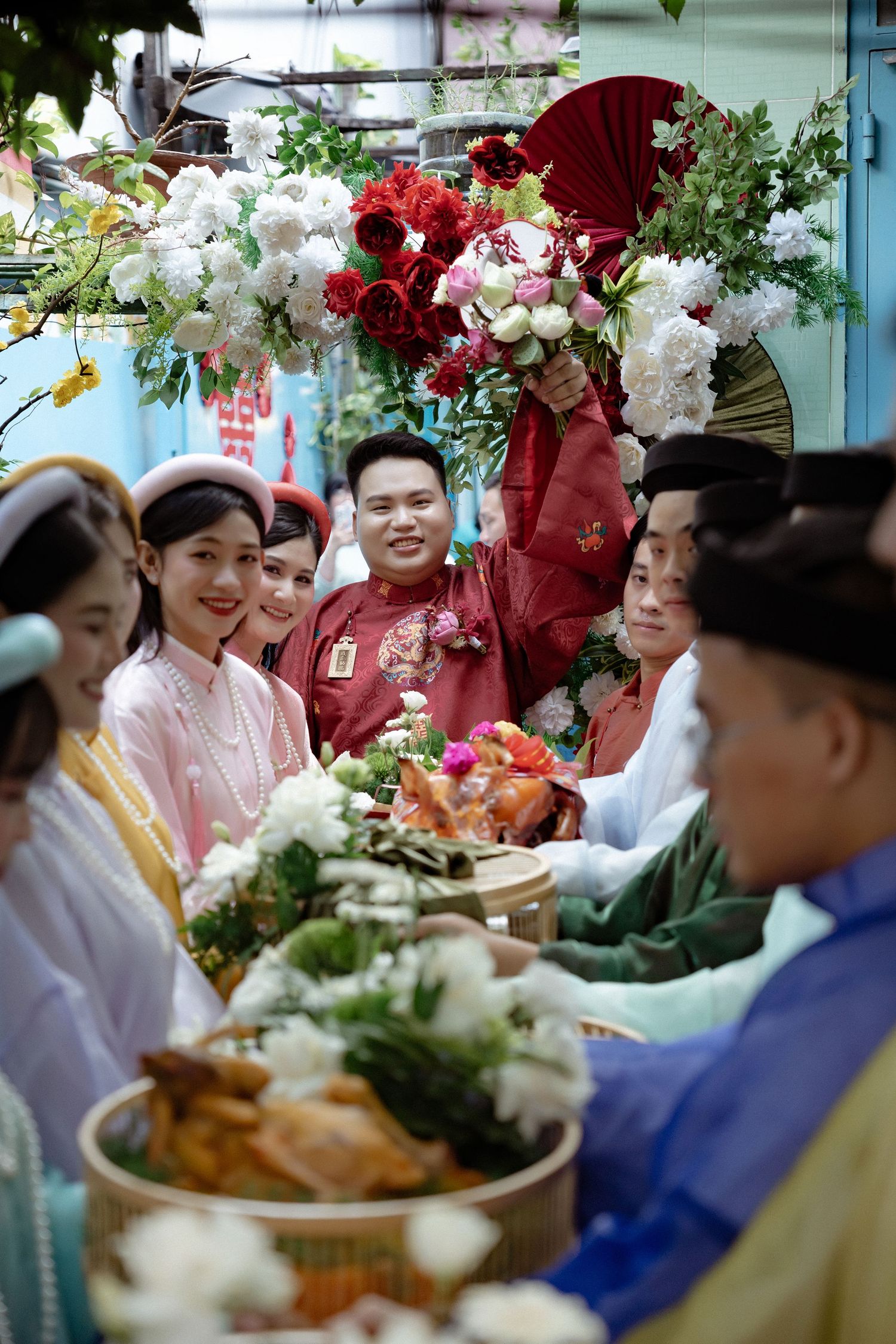 A festive gathering with traditional dress, flowers and food dishes on a decorative table.