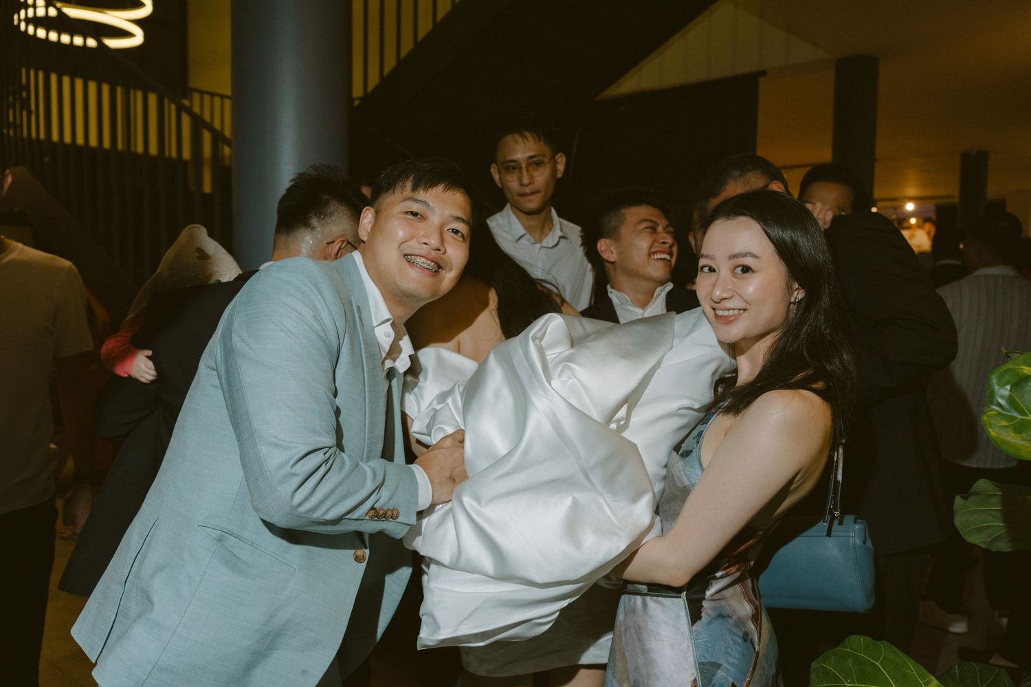 Wedding guests having fun and laughing together on the dance floor at an evening reception.