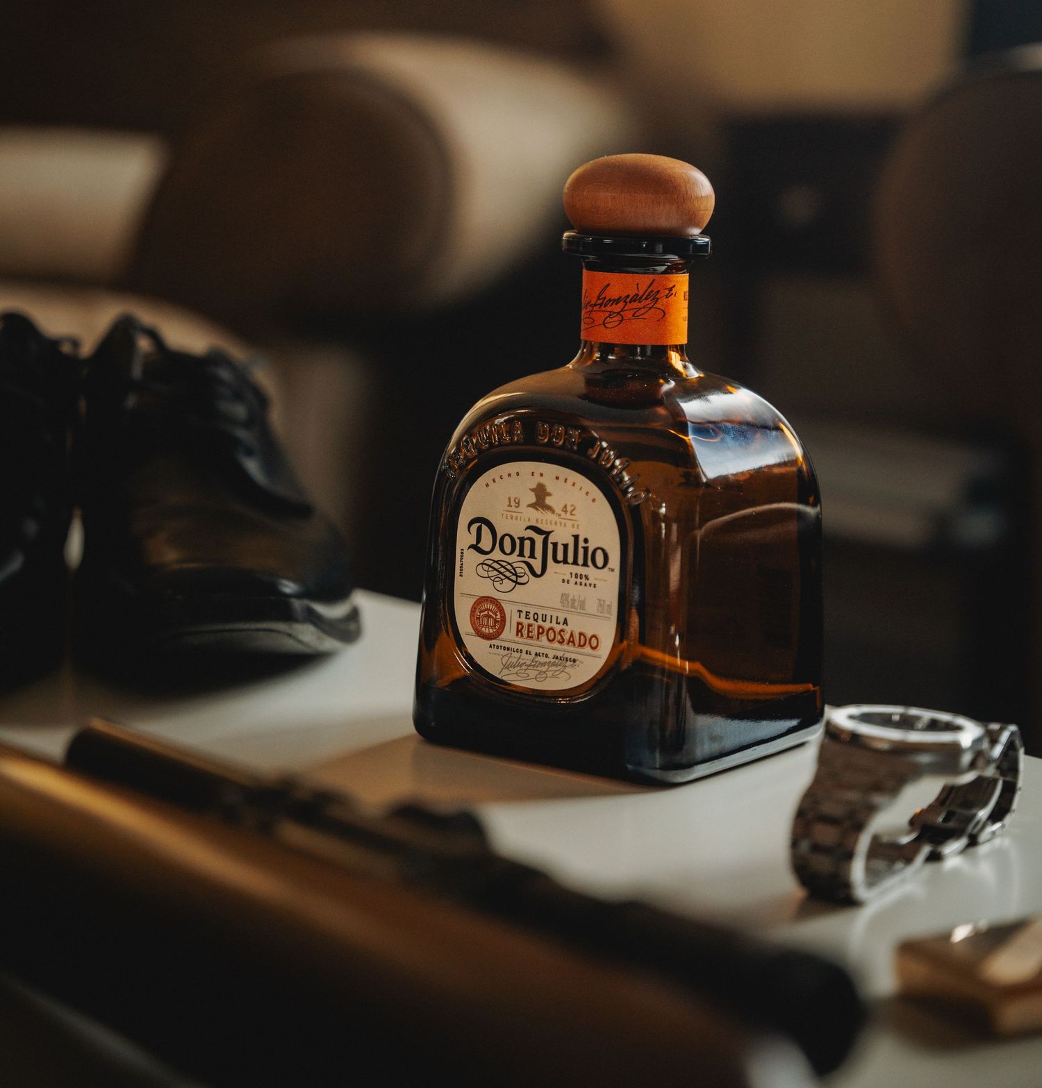 Bottle of Don Julio tequila captured in moody ambient lighting with dark elements in the background.