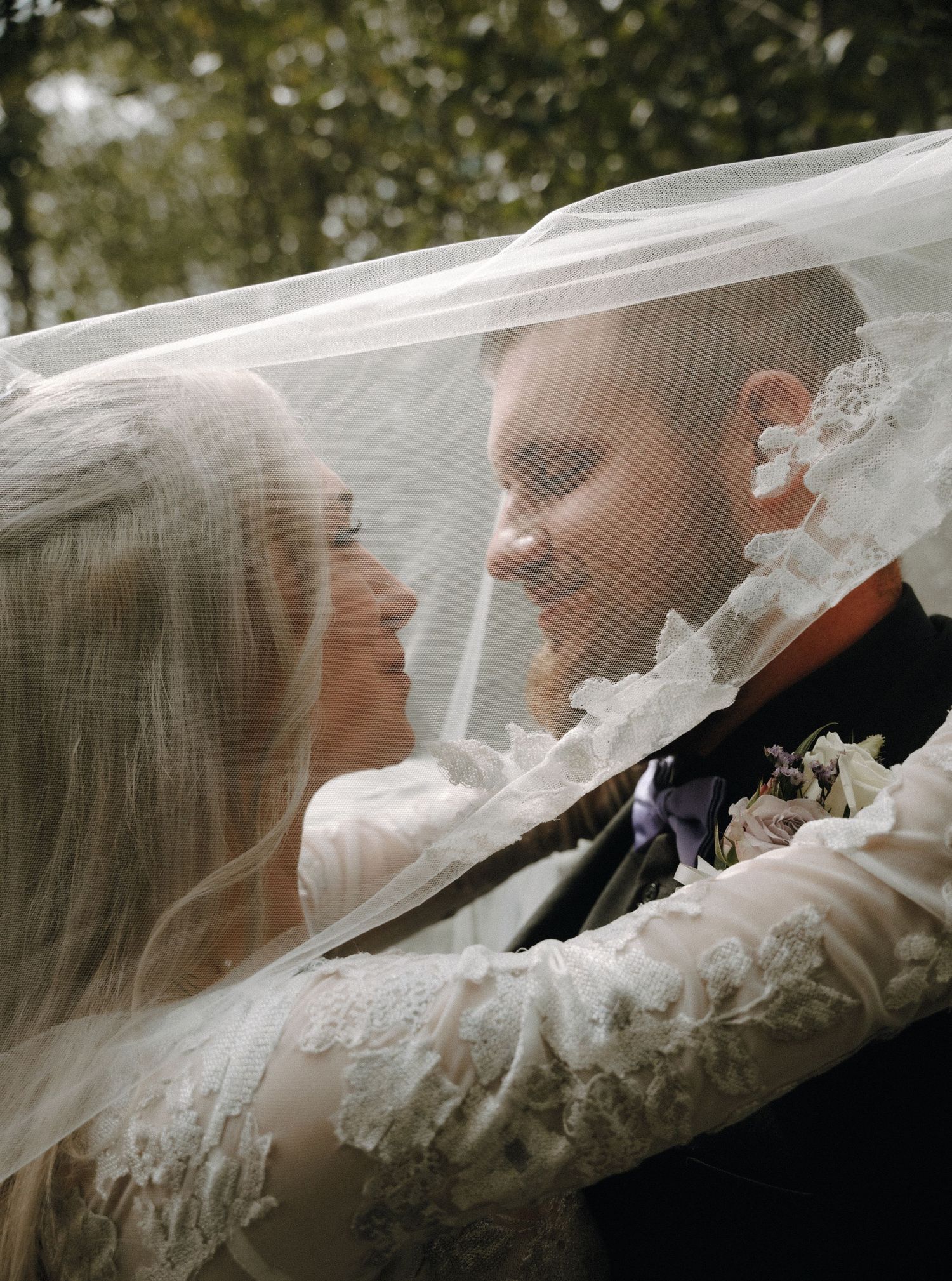 A romantic wedding moment captured with the couple's faces close together under a delicate lace veil.