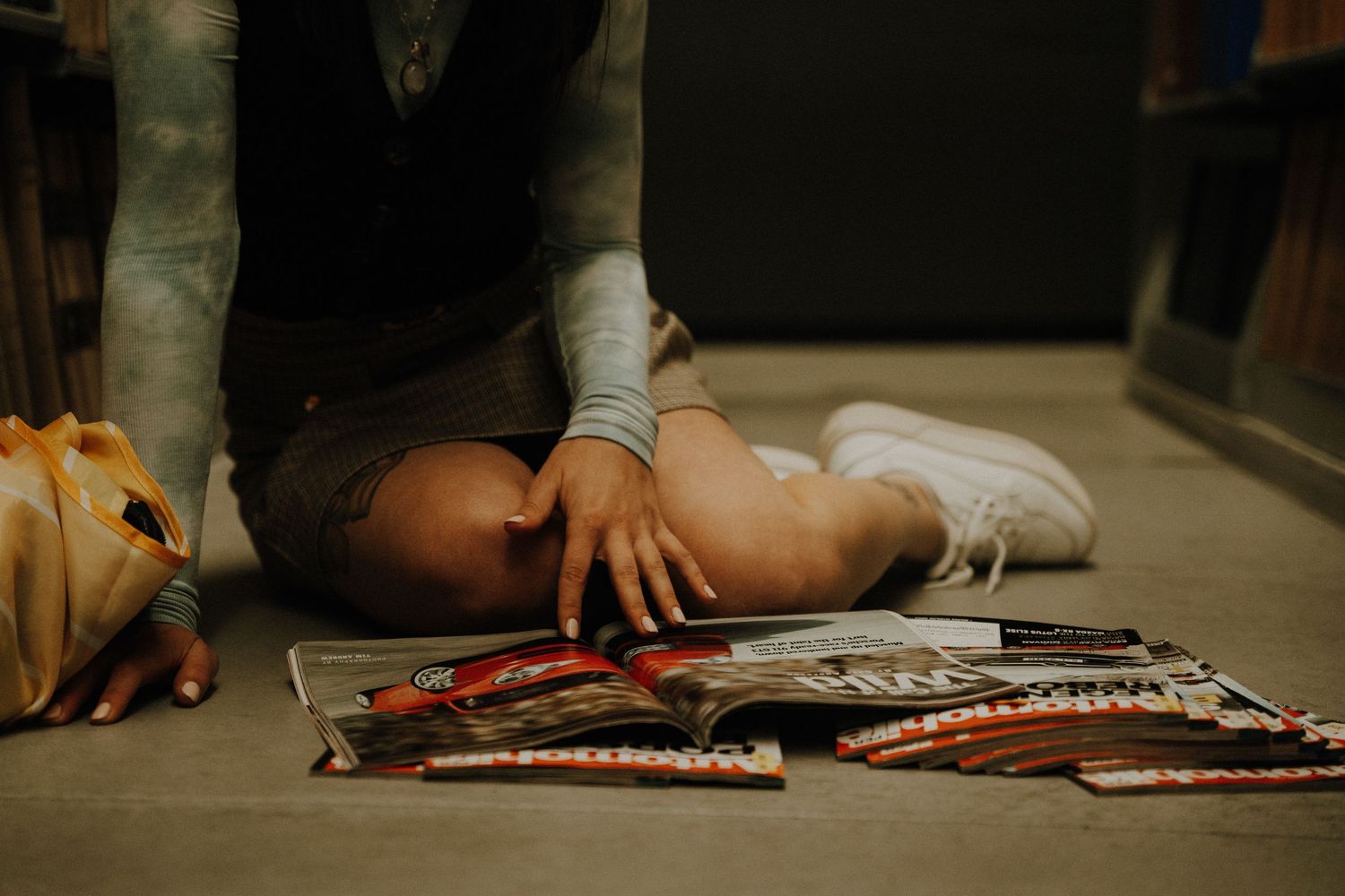 Someone sitting on floor surrounded by candy bars and snacks reaching down to grab something.