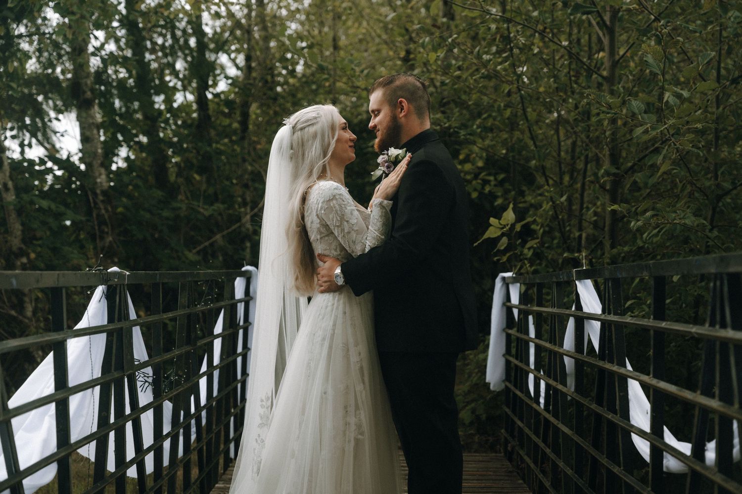 Romantic couple photos taken on a wooden bridge surrounded by trees.