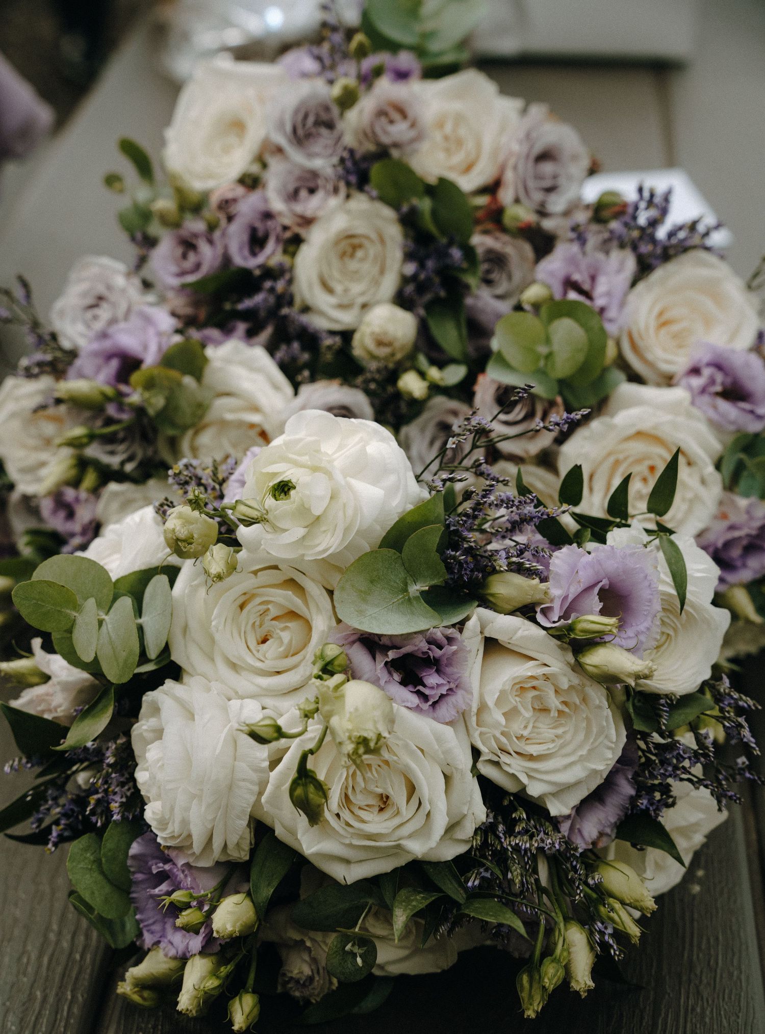 Elegant floral arrangement featuring white roses and purple blooms artfully displayed on a rustic wooden surface.