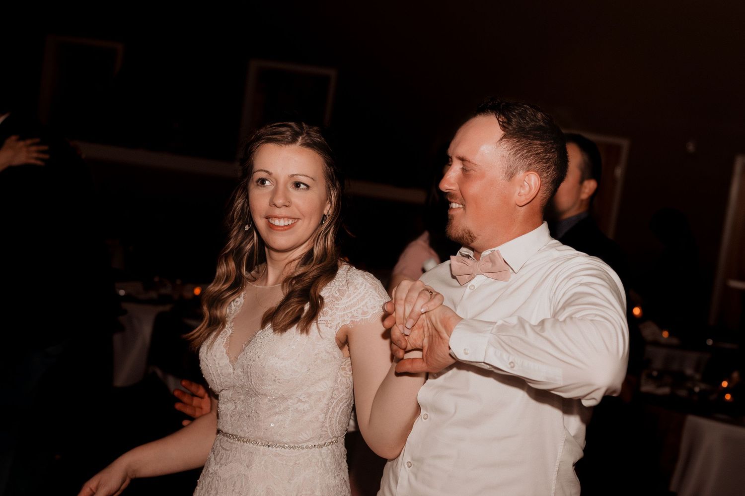 Wedding reception dance captured in low light with joyful movements.
