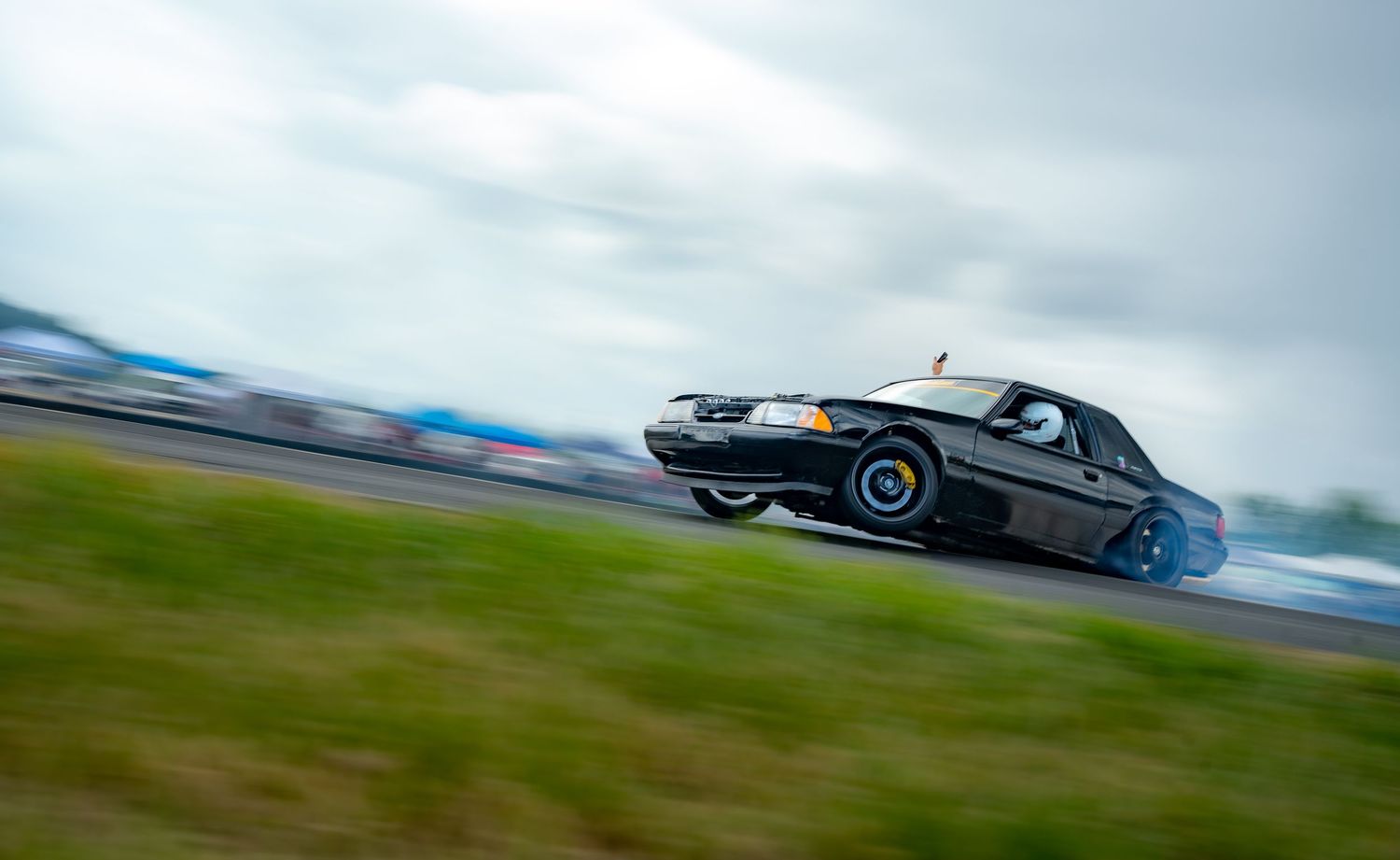 Six racing cars speeding down a racetrack with motion blur effect captured during an intense competition.