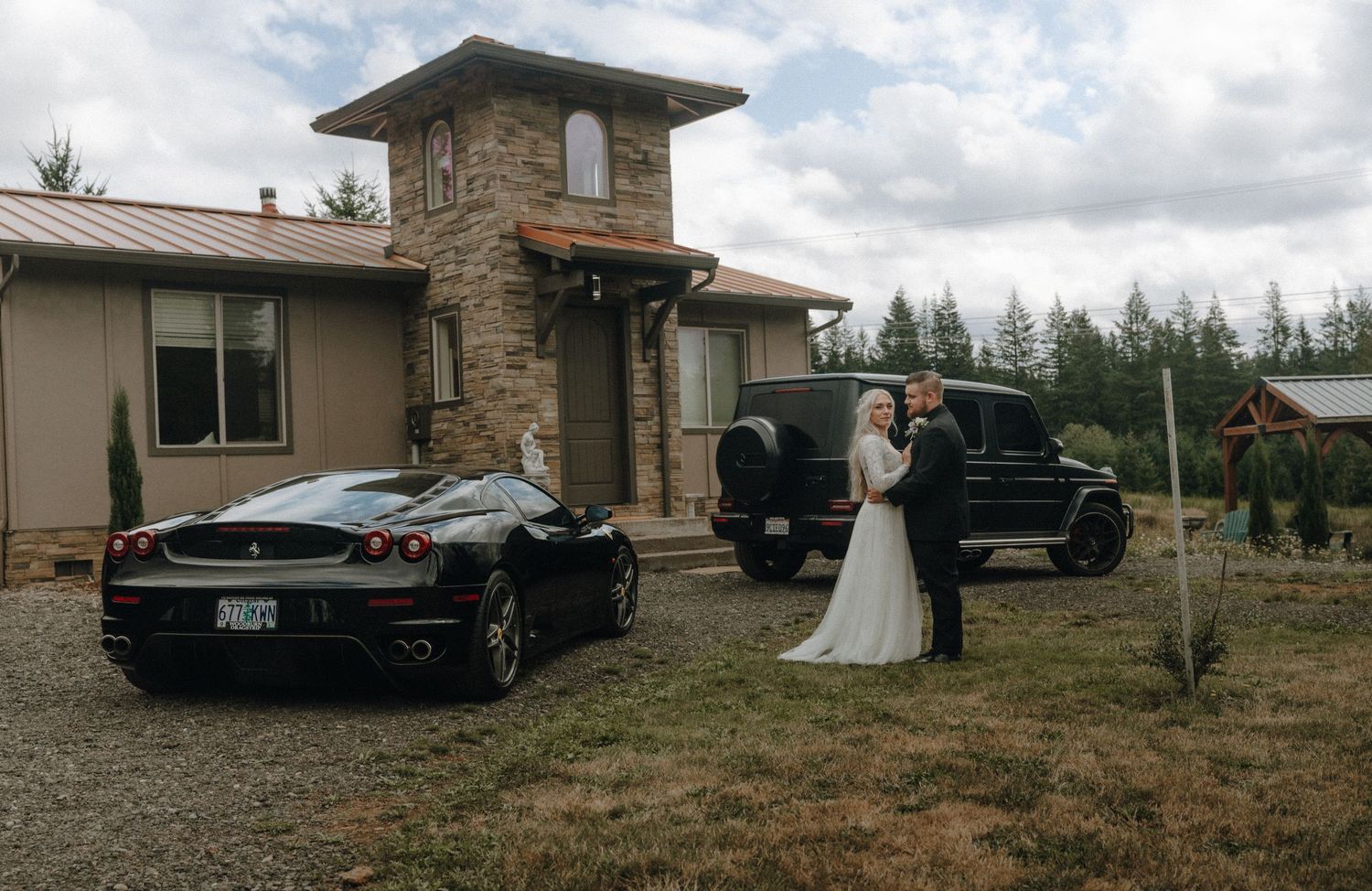 A wedding scene outside a stone-accented house with a black Ferrari and SUV parked on the gravel.