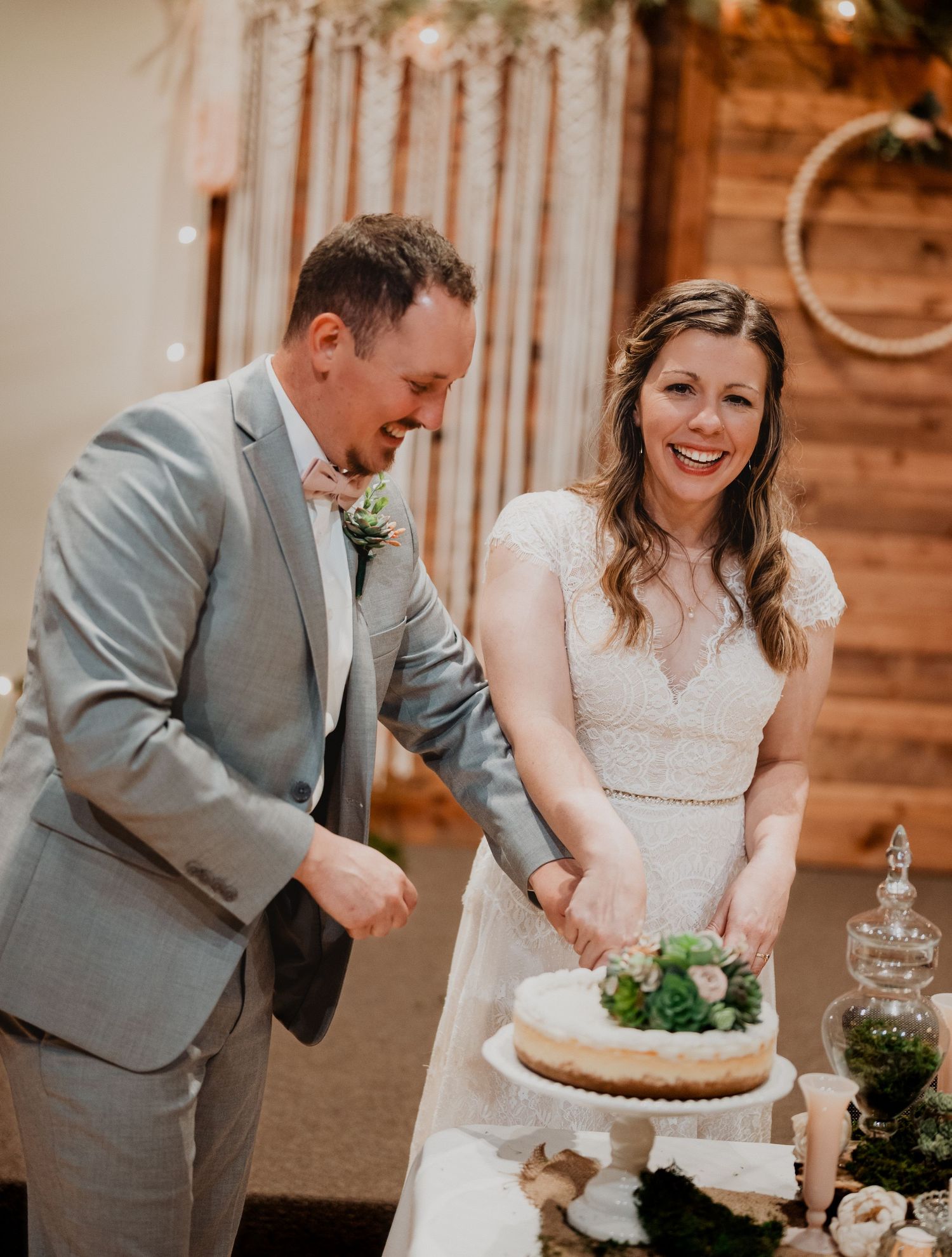Wedding couple laughs while cutting their cake together at reception.