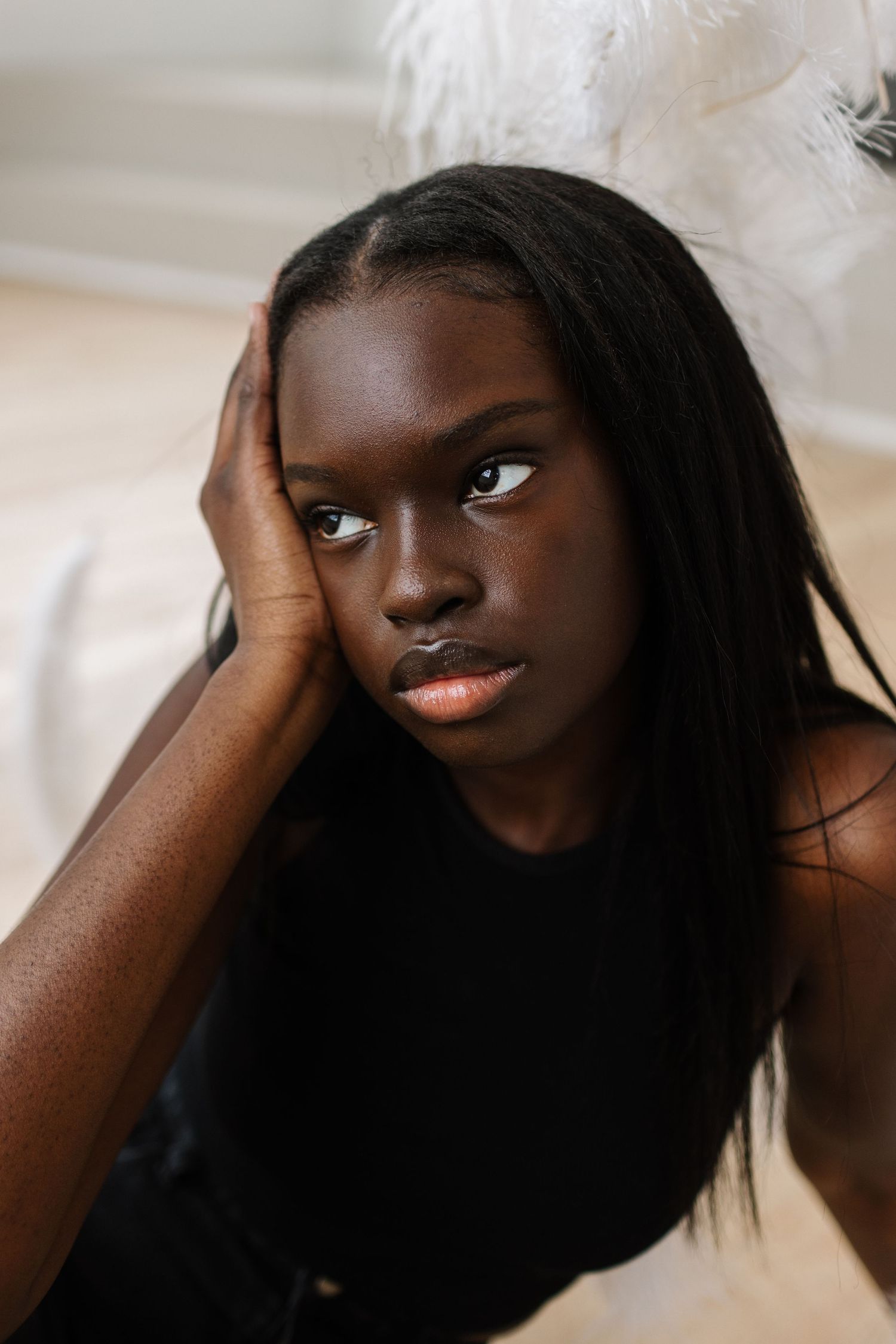 Close-up portrait with dark hair against light background showcasing natural beauty in a black top.