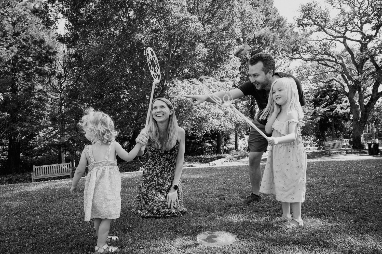 People playing in a backyard garden on a sunny day, captured in black and white.