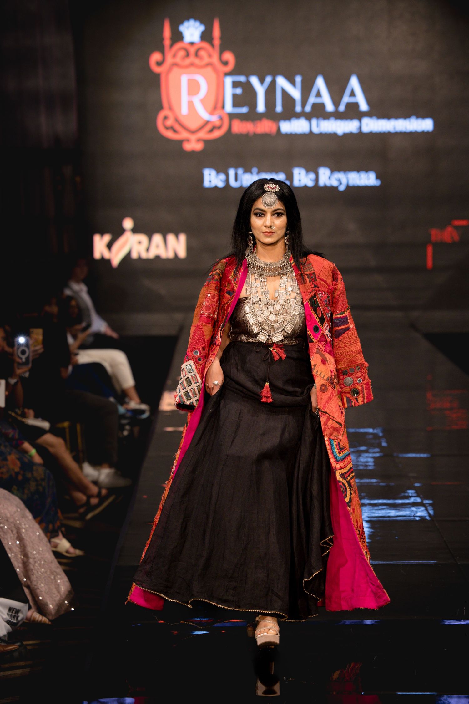 Fashion model walks runway in traditional fusion outfit at Reynaa fashion show.