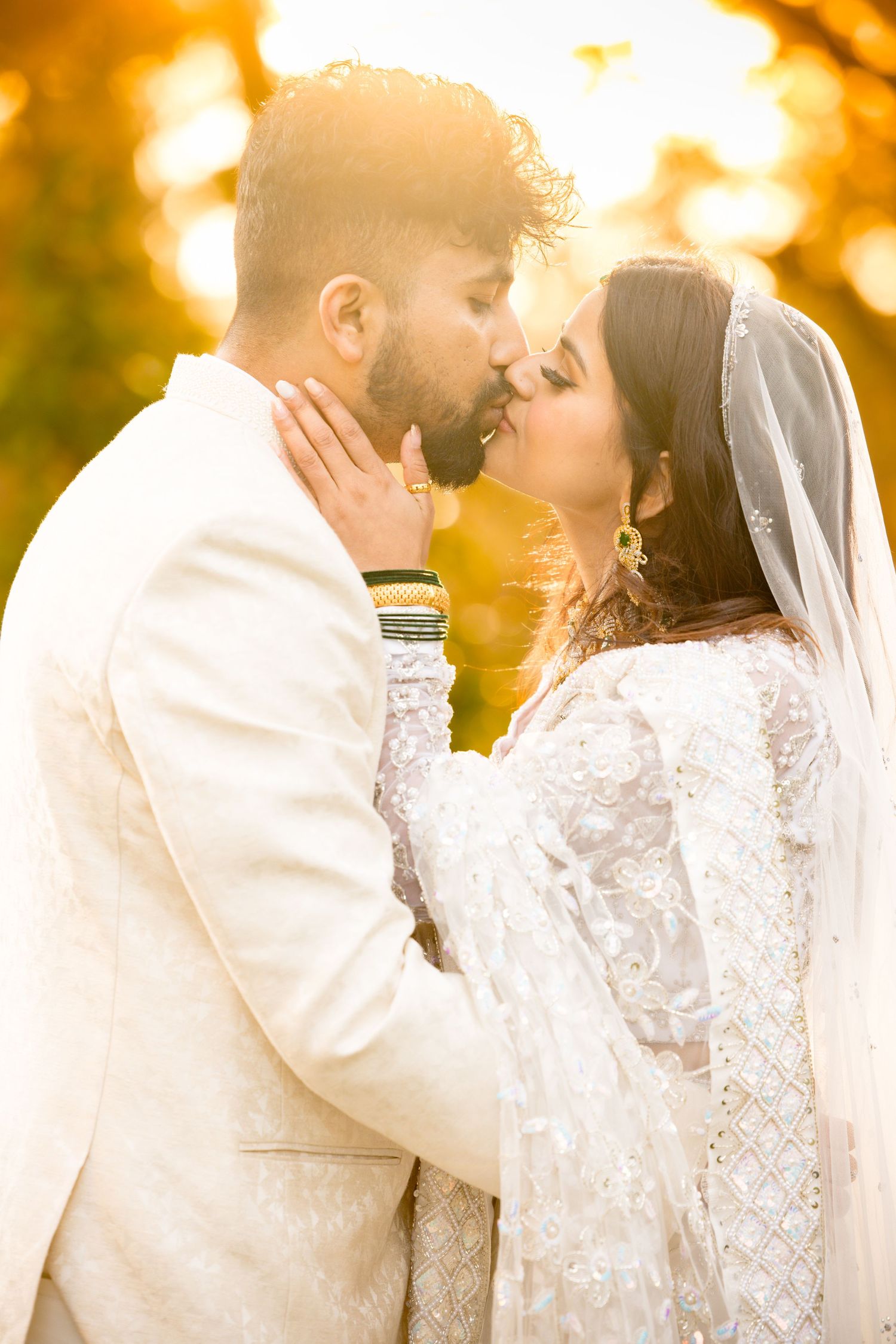 A tender wedding moment captured during golden hour with warm autumn colors in the background.