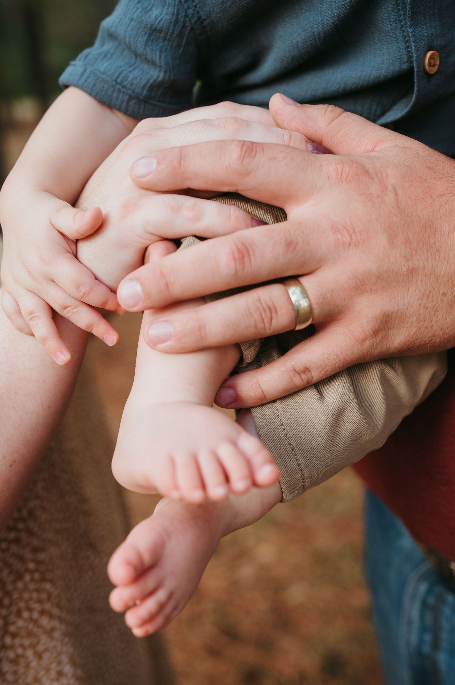 detail shot of parents holding the hands and legs of their soon to be 1 year old first born son.