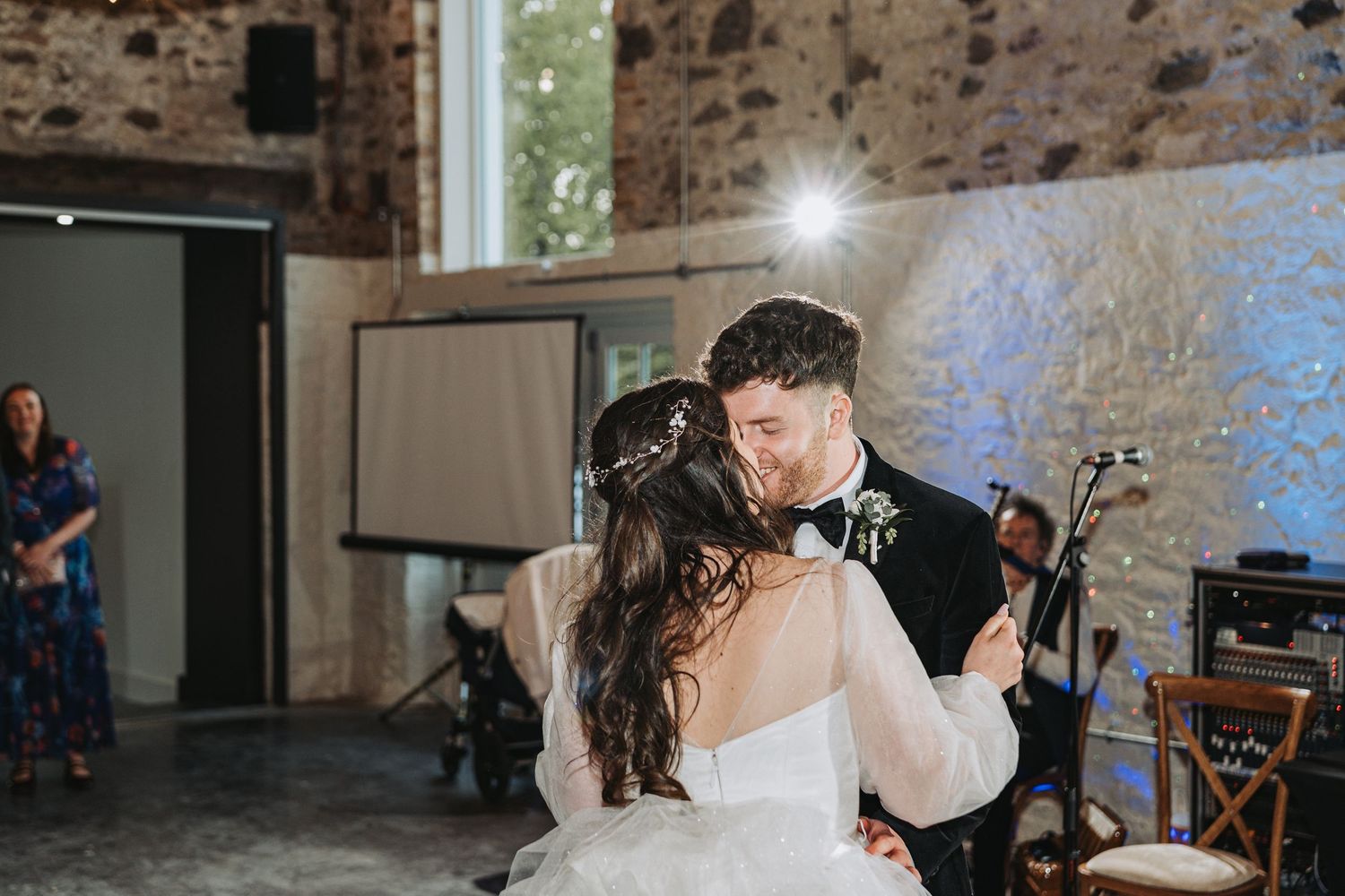 Couple shares their first dance as newlyweds in the rustic Kinclune Steading with stone walls and twinkling lights.