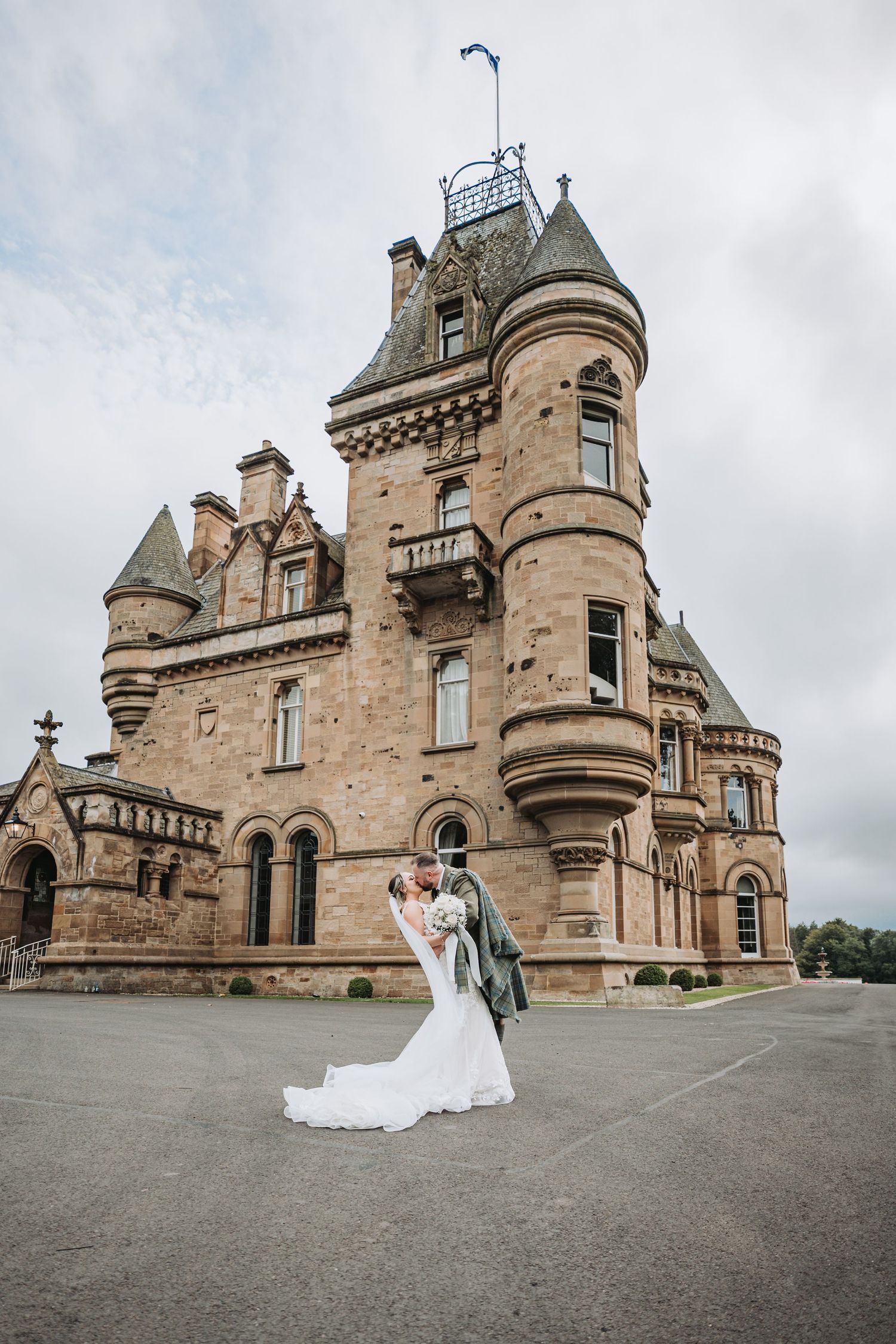 A romantic wedding photo captured outside grand Scottish baronial Cornhill Castle with ornate turrets and stone architecture.
