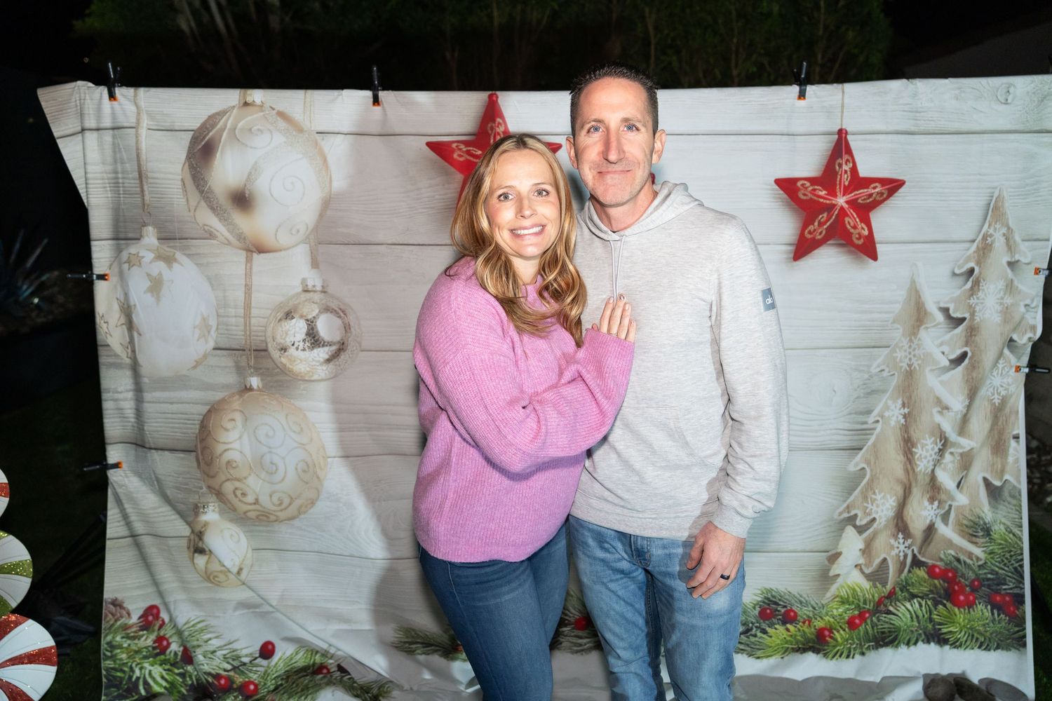 girl wearing a pink sweater, boy wearing a cream sweater, Christmas backdrop