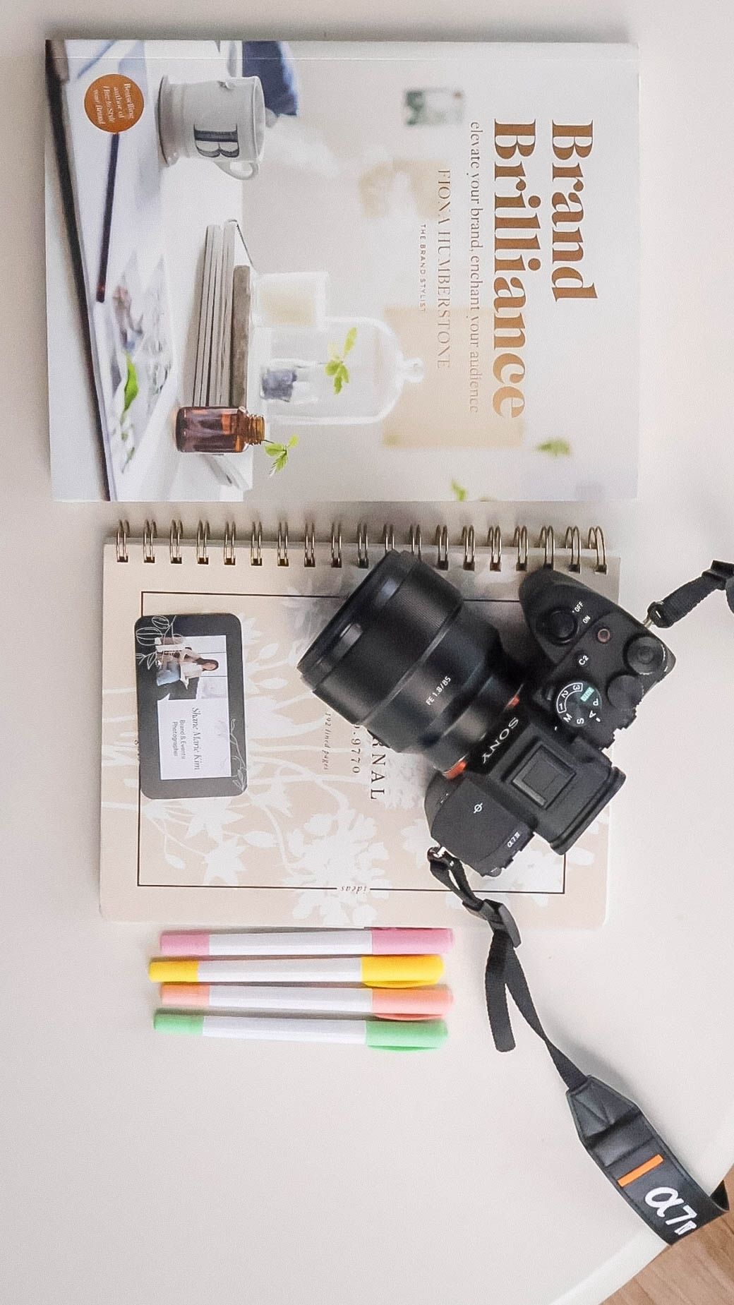 book, business card, Sony camera, highlighter markers, flat lay
