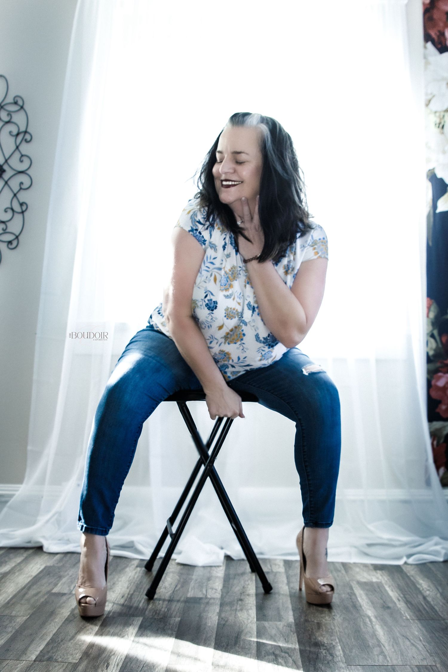 Casual portrait of woman laughing while sitting on folding stool.