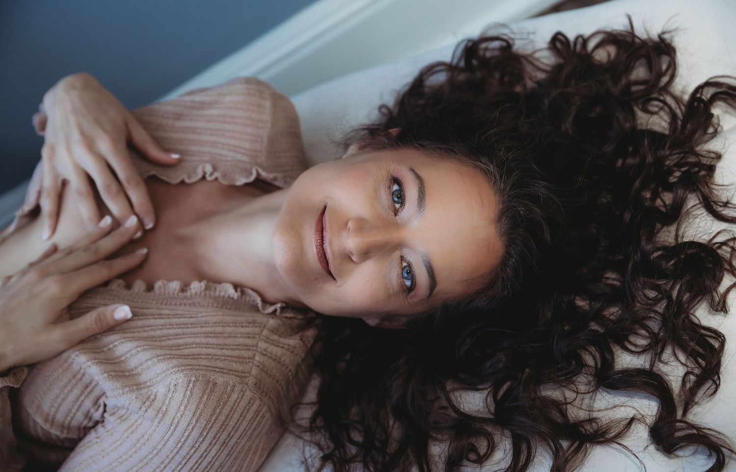 Intimate boudoir portrait with soft lighting and neutral tones.