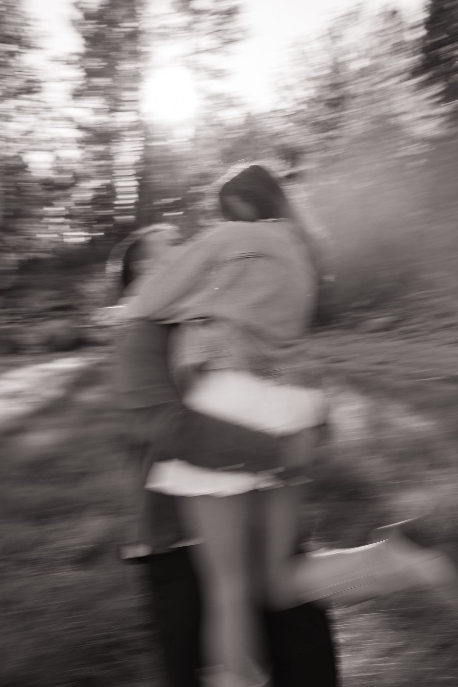 A blurry motion sequence shows a person in casual attire moving across a forest landscape in black and white.