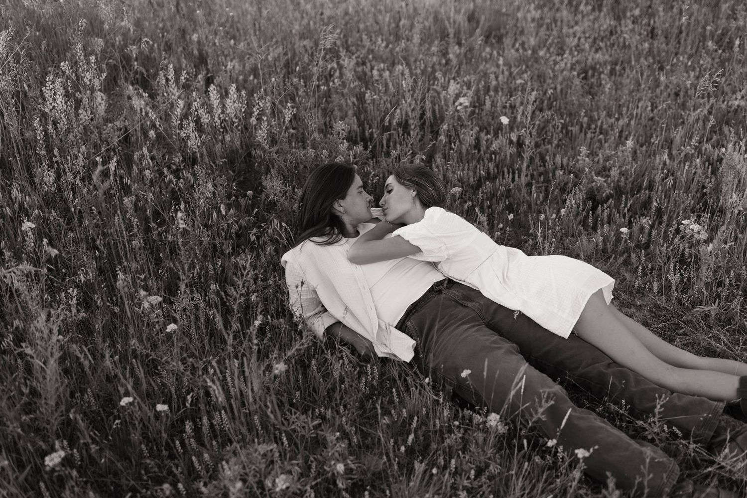 A sequential series of grayscale photographs showing someone rolling playfully down a grassy hill.