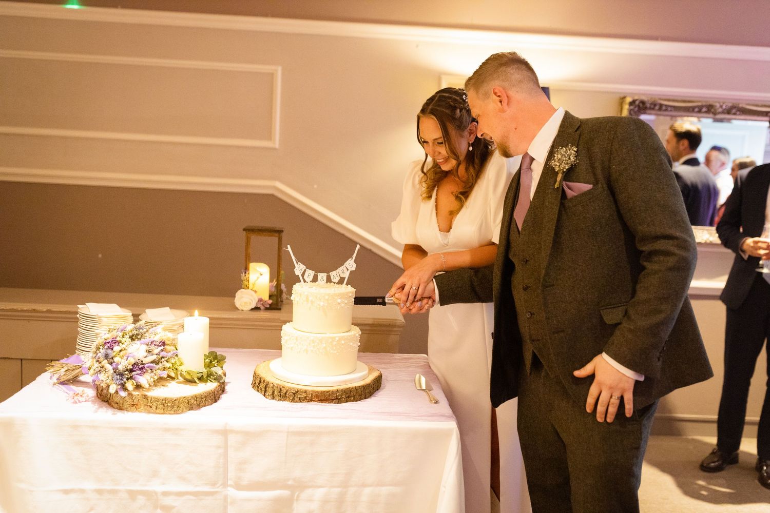 A couple together cutting their elegant two-tier wedding cake at their reception.
