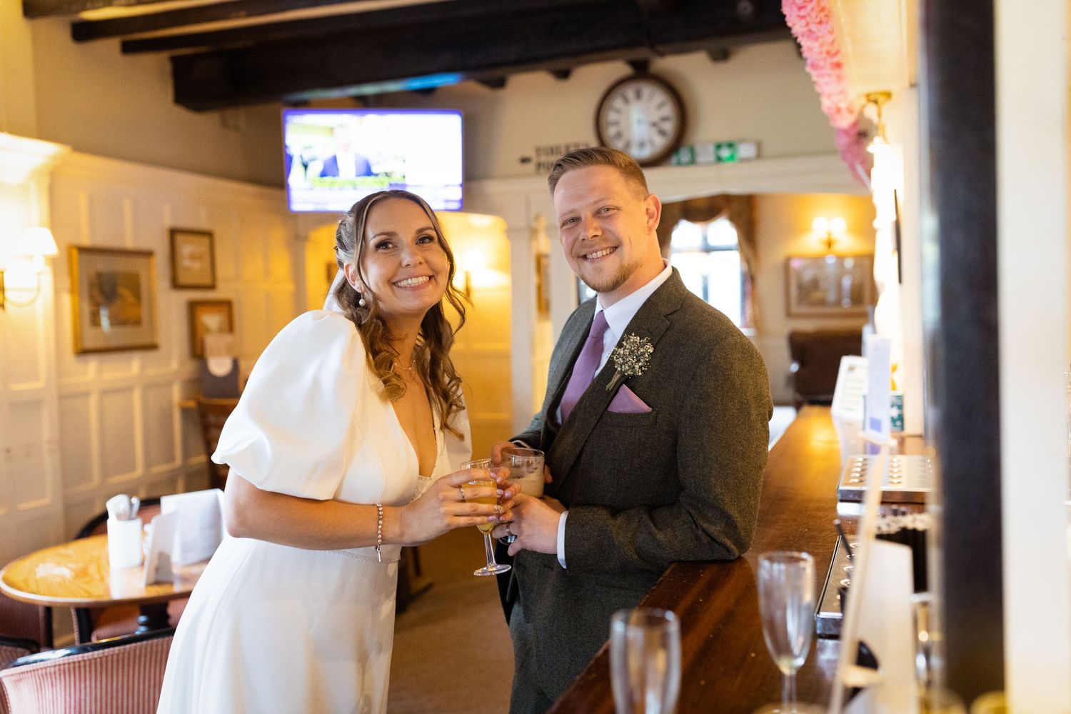 A bride and groom share a joyful moment together at a pub reception venue with rustic wood beams and warm lighting.