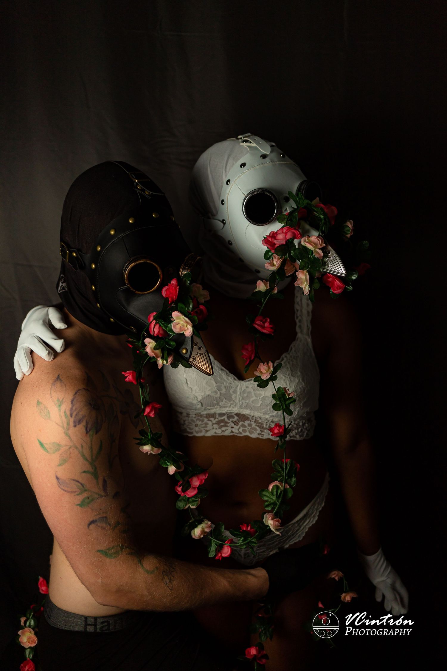 Artistic portrait featuring black and white masks with red roses intertwined in a dark and moody setting.