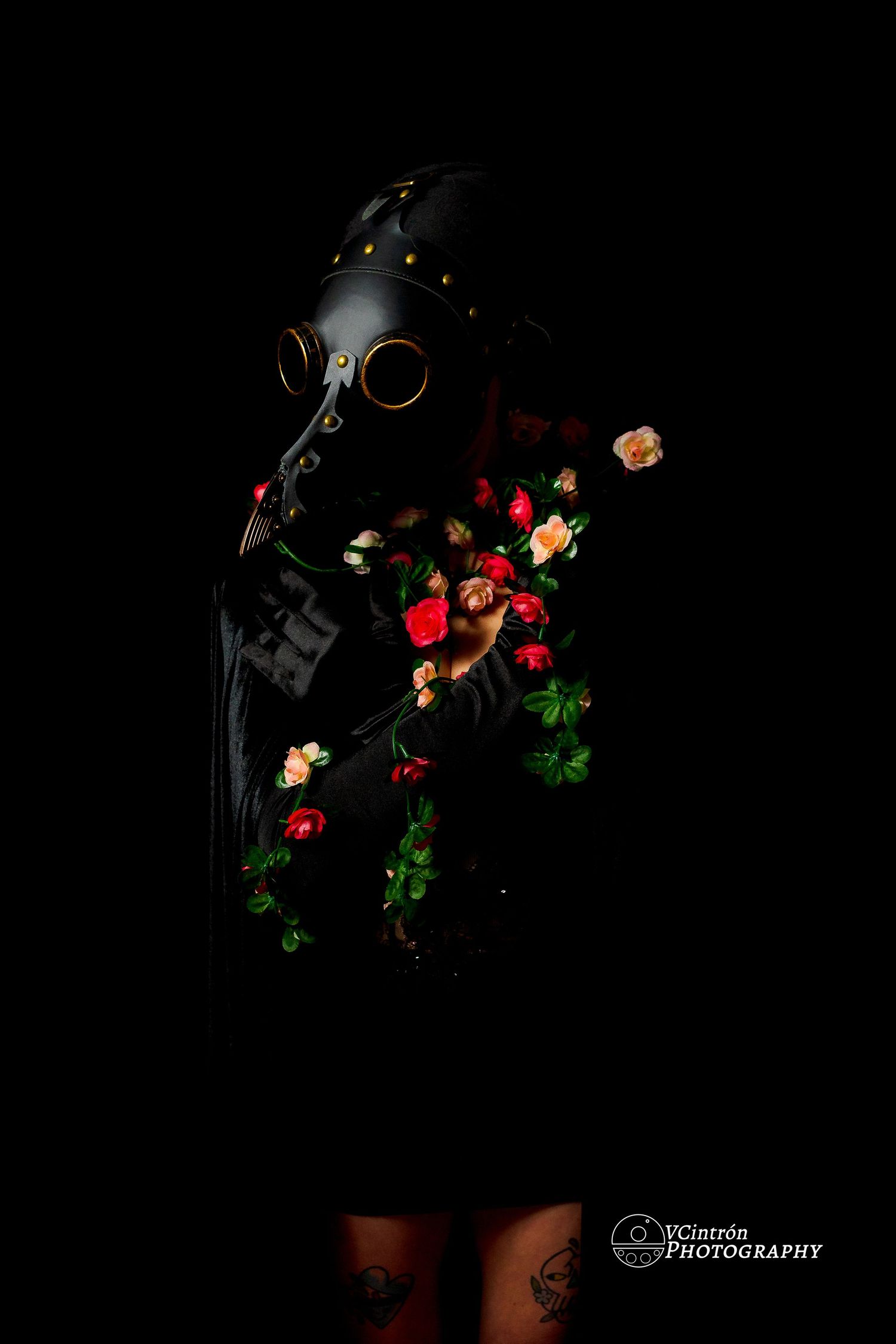 Dark still life with luminous coffee beans and rose petals arranged in swirling patterns against black background.