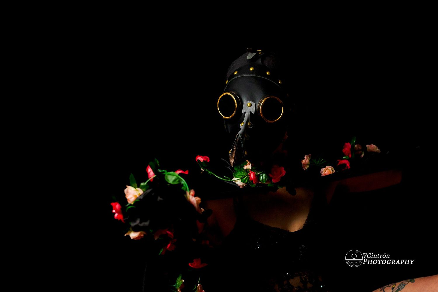 A dark artistic composition featuring a gas mask surrounded by glowing green and red lights against a black background.