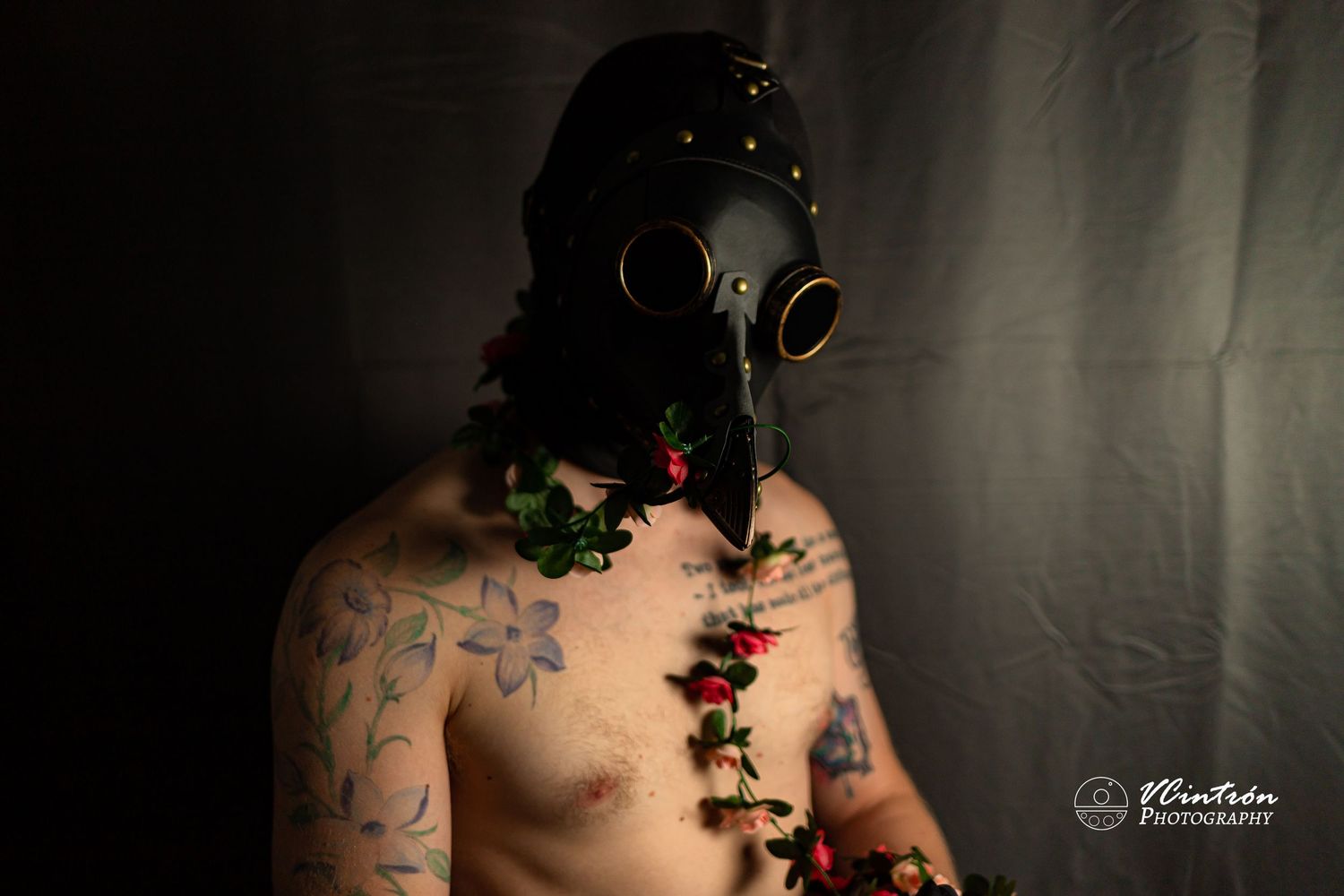Artistic portrait of gas mask wearer with vines and flowers growing from chest in moody lighting.