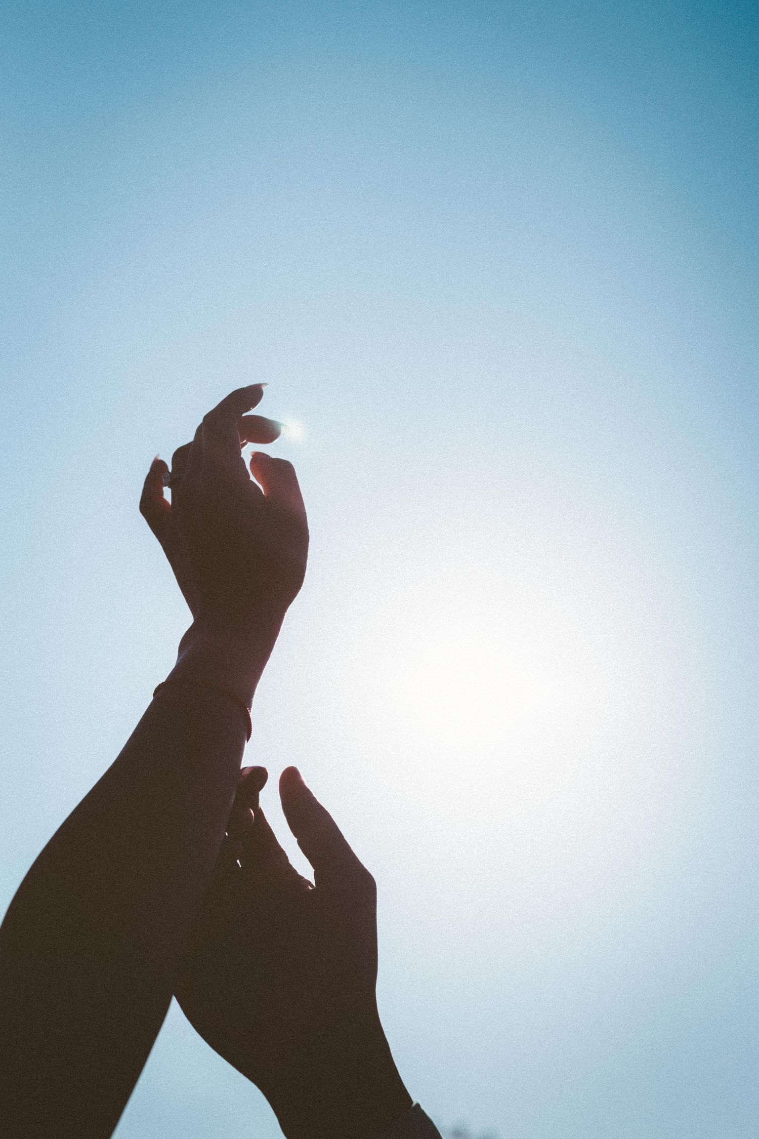 A sequence of silhouetted figures reaching skyward against a light blue background.