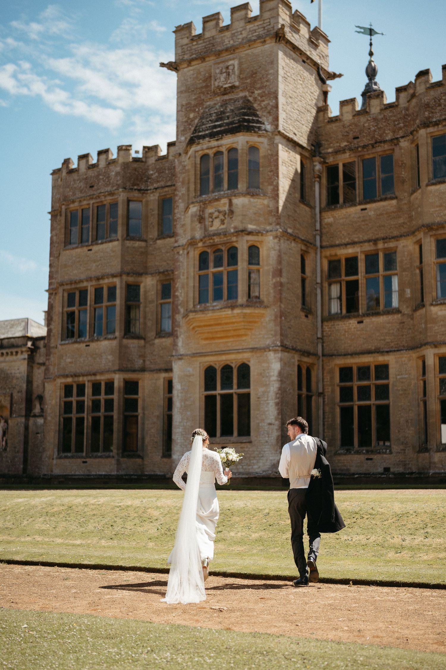 Gothic stone manor house with crenellated walls and mullioned windows on a sunny day.