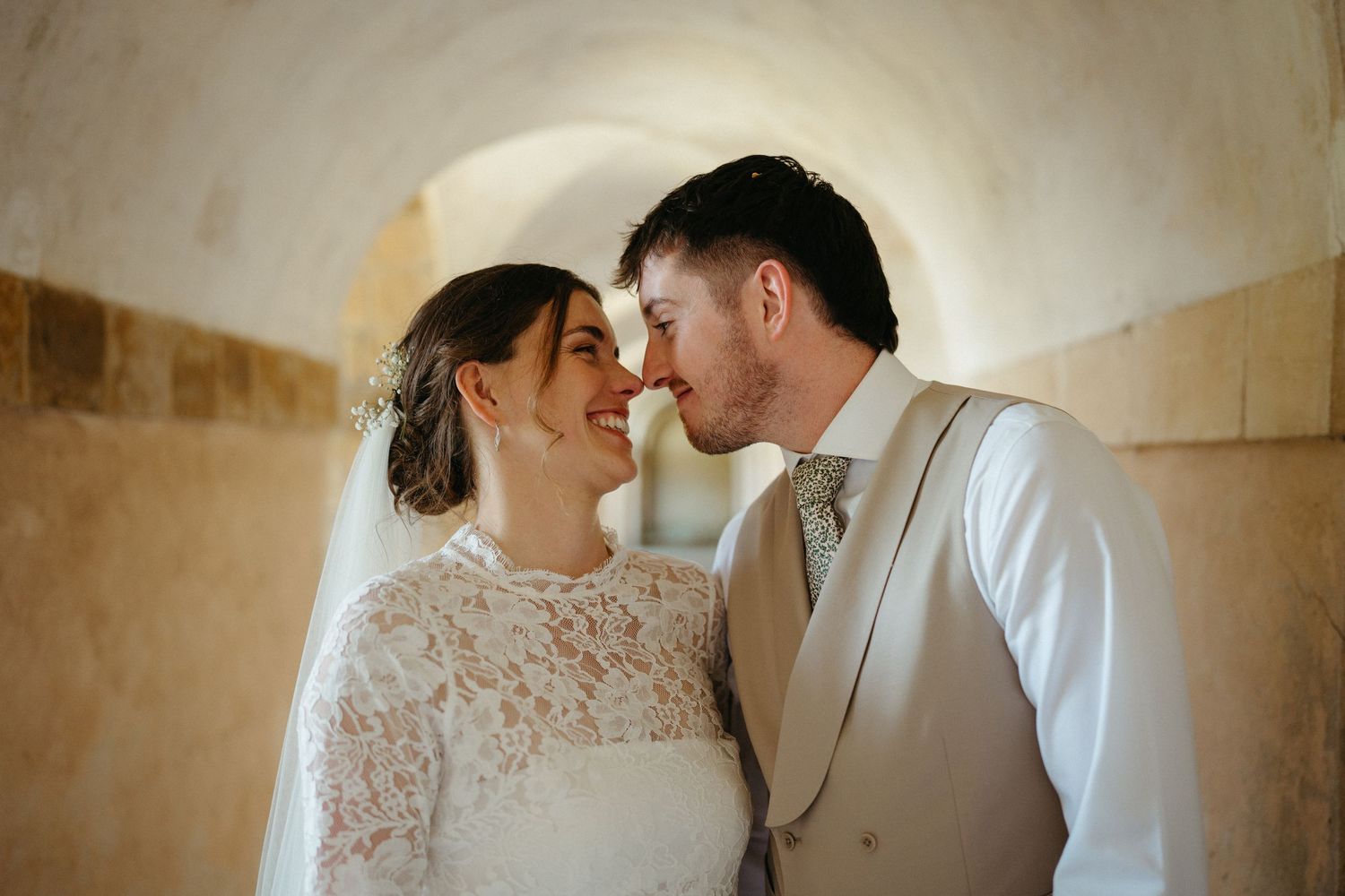 An intimate wedding moment captured in a vaulted stone passageway.