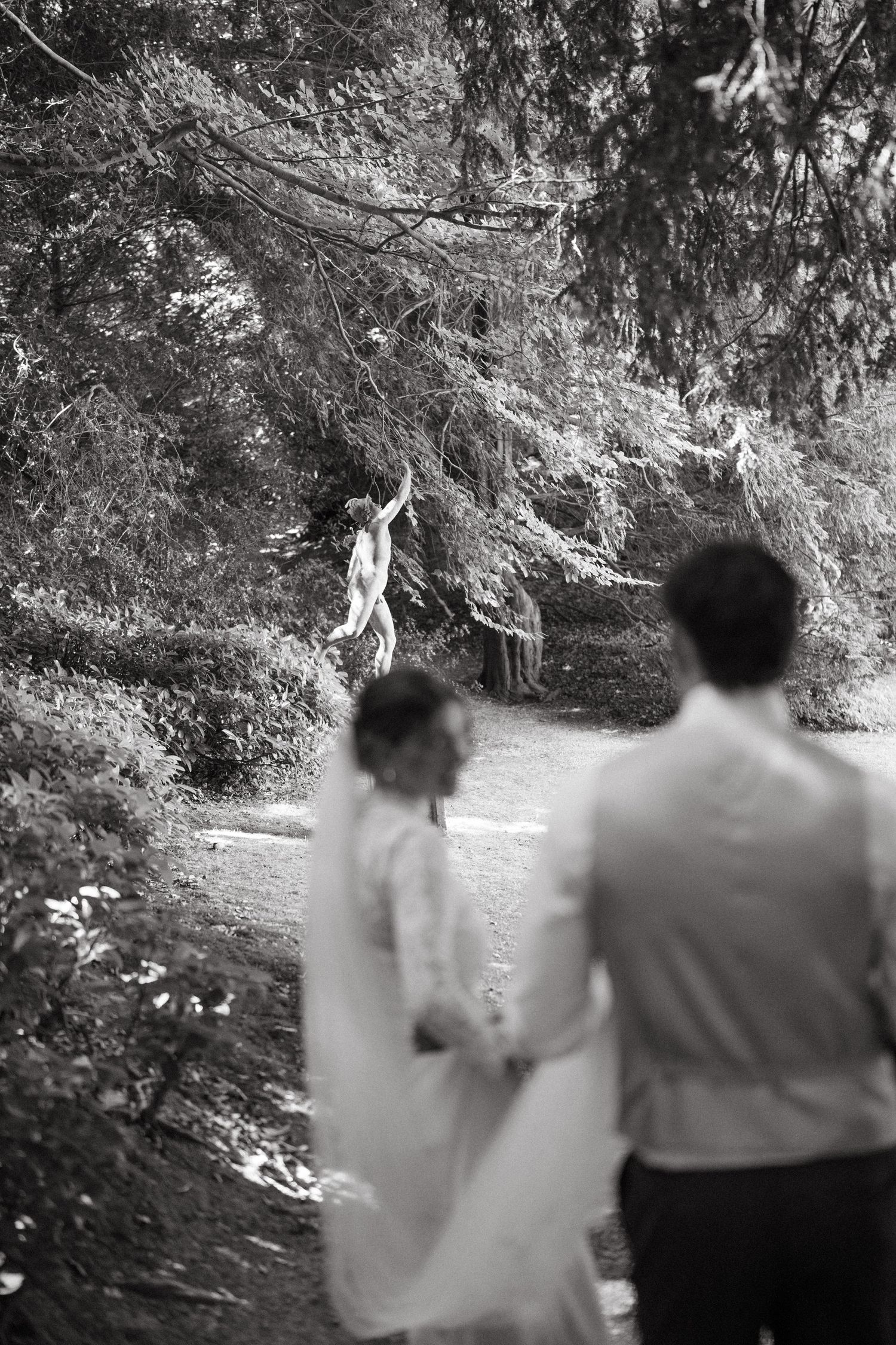 Black and white photo of figures walking through a wooded path.