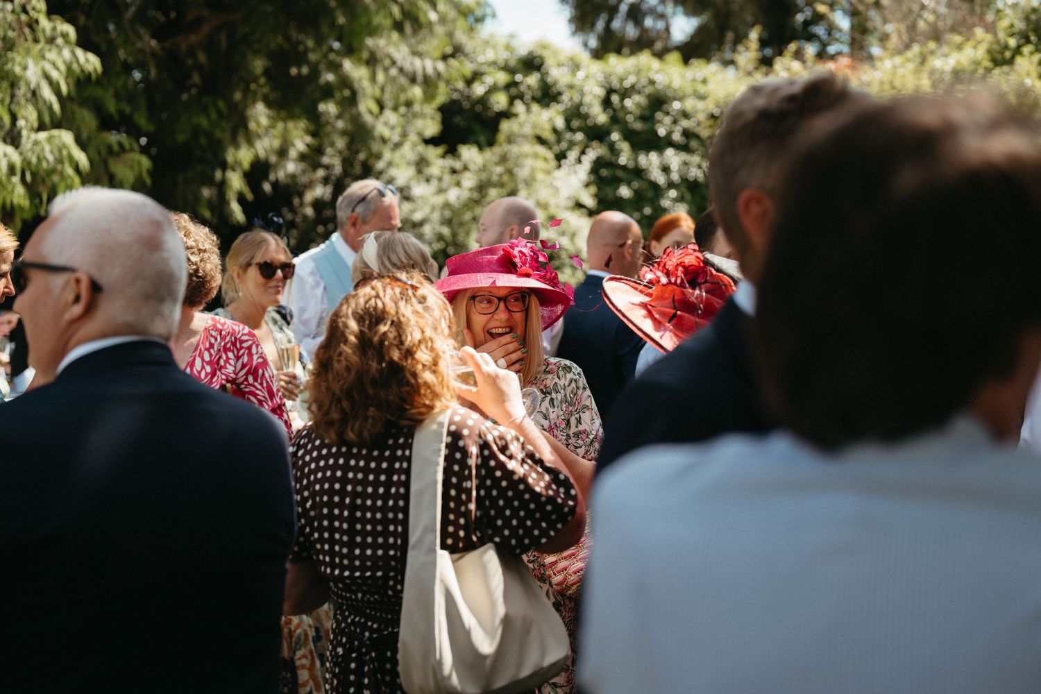 Wedding guests mingle in a sunny garden during the reception celebration.