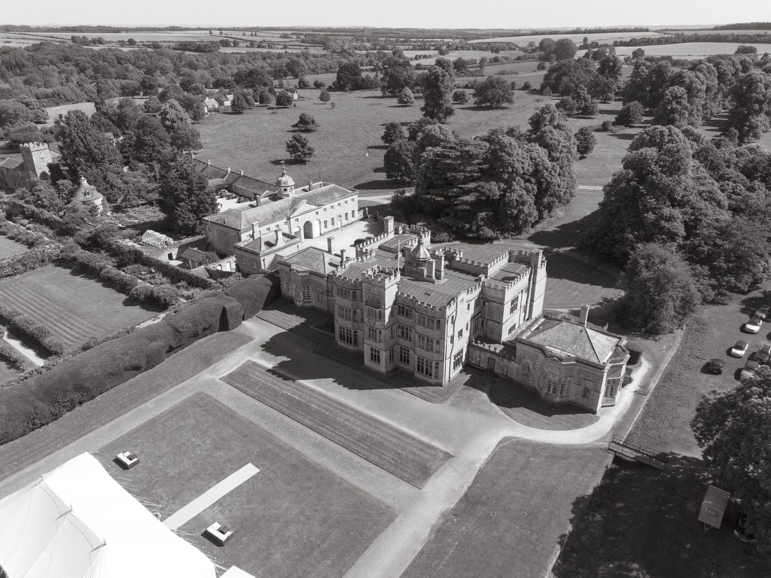 Aerial panoramic view of a historic estate with manicured lawns and surrounding countryside.