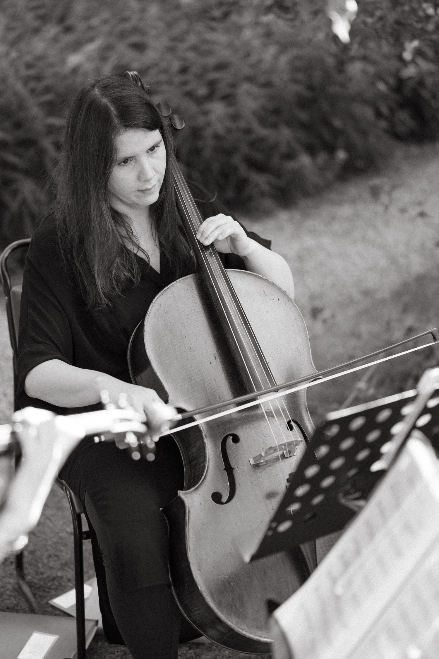 Musicians perform classical music with string instruments in a garden setting.
