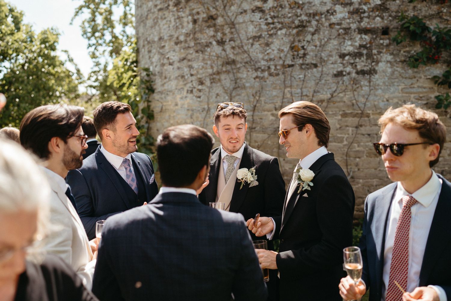 Guests in formal attire socialize during an outdoor wedding reception.
