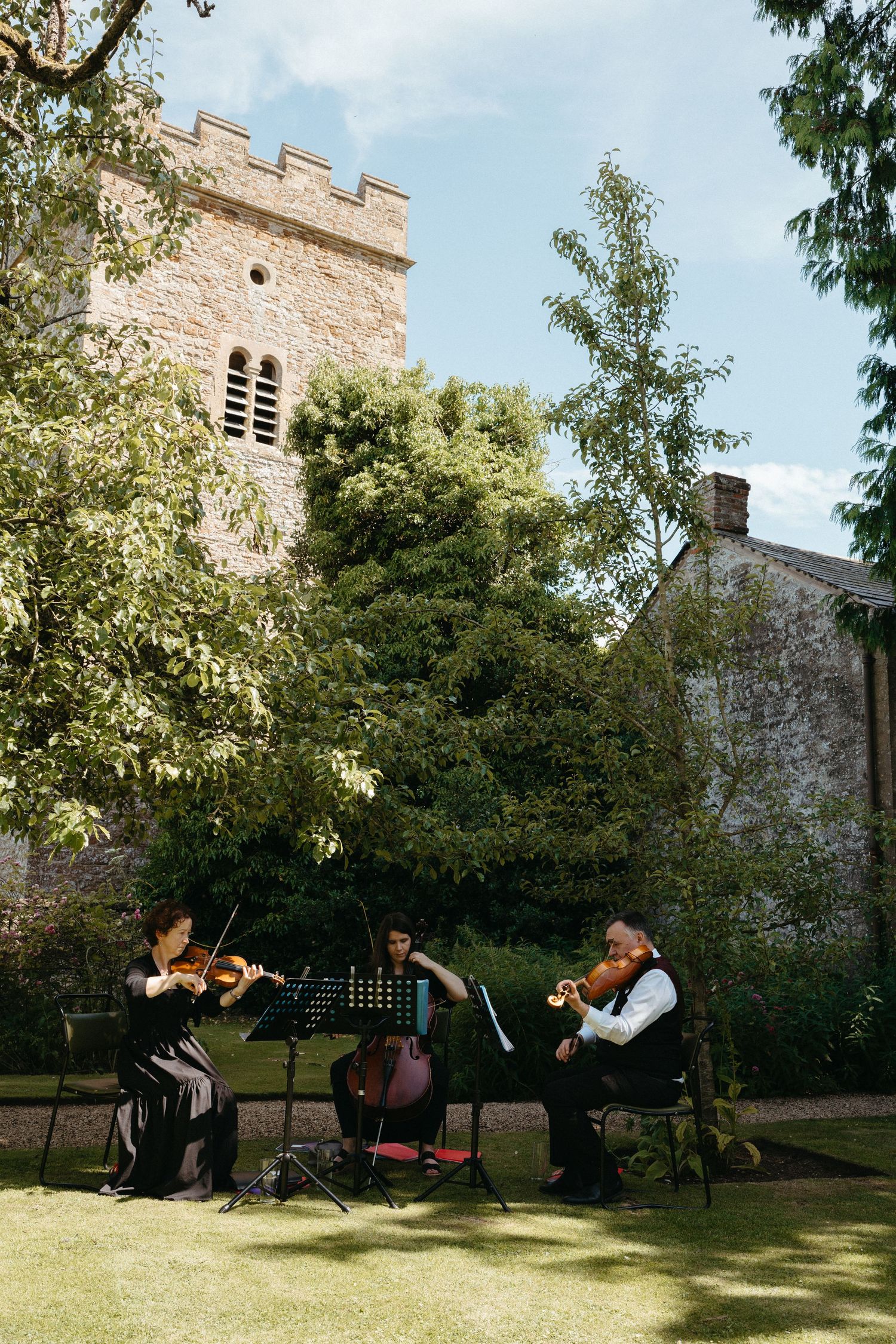 String quartet performs on the lawn in front of a historic stone church.