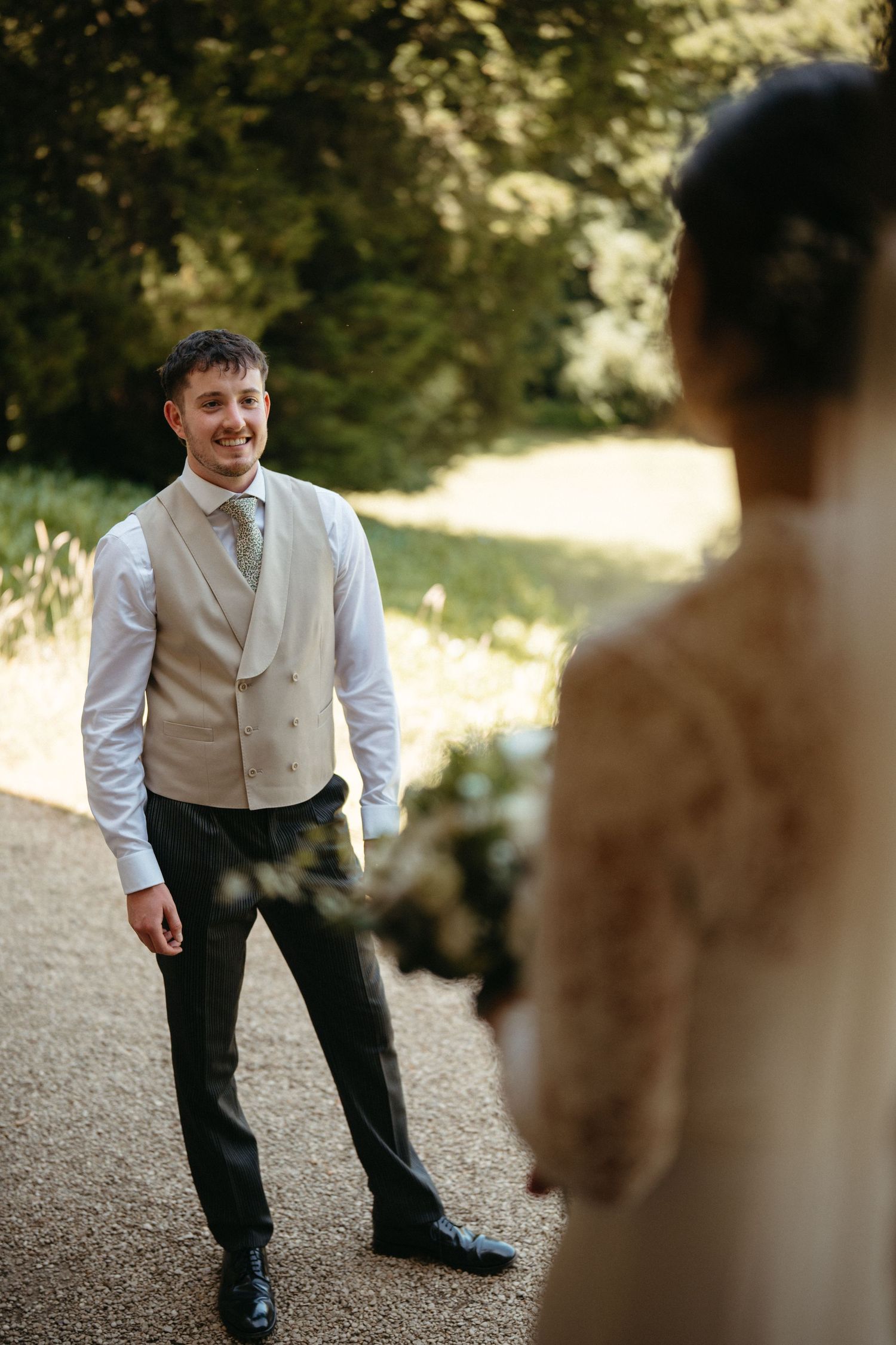 A playful moment captured of a person in formal wear leaning forward against a natural outdoor backdrop.