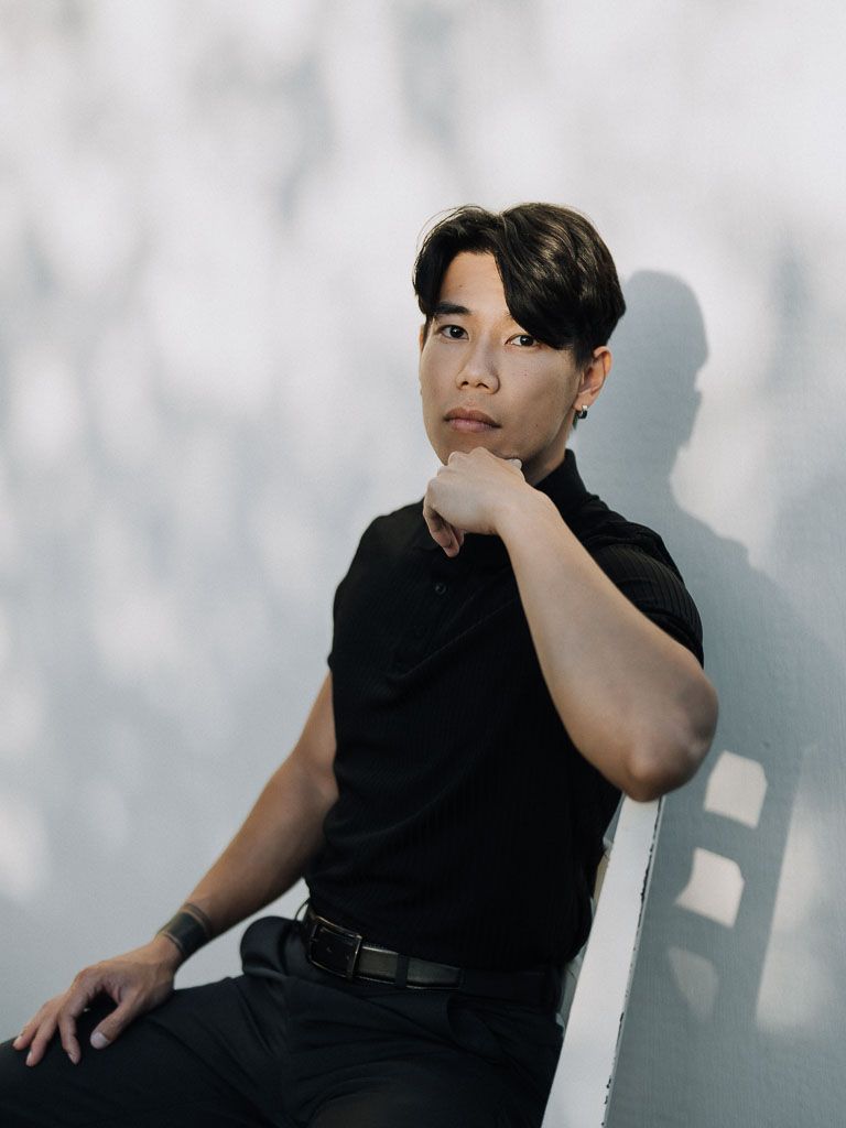 Thoughtful studio portrait with dramatic shadows against a light background.