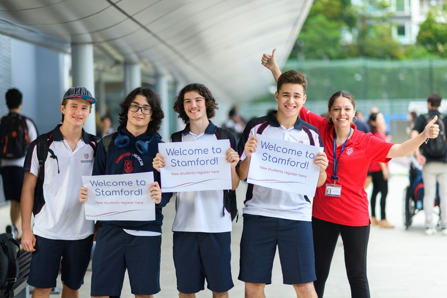 Group of students holding signs while walking under covered walkway.