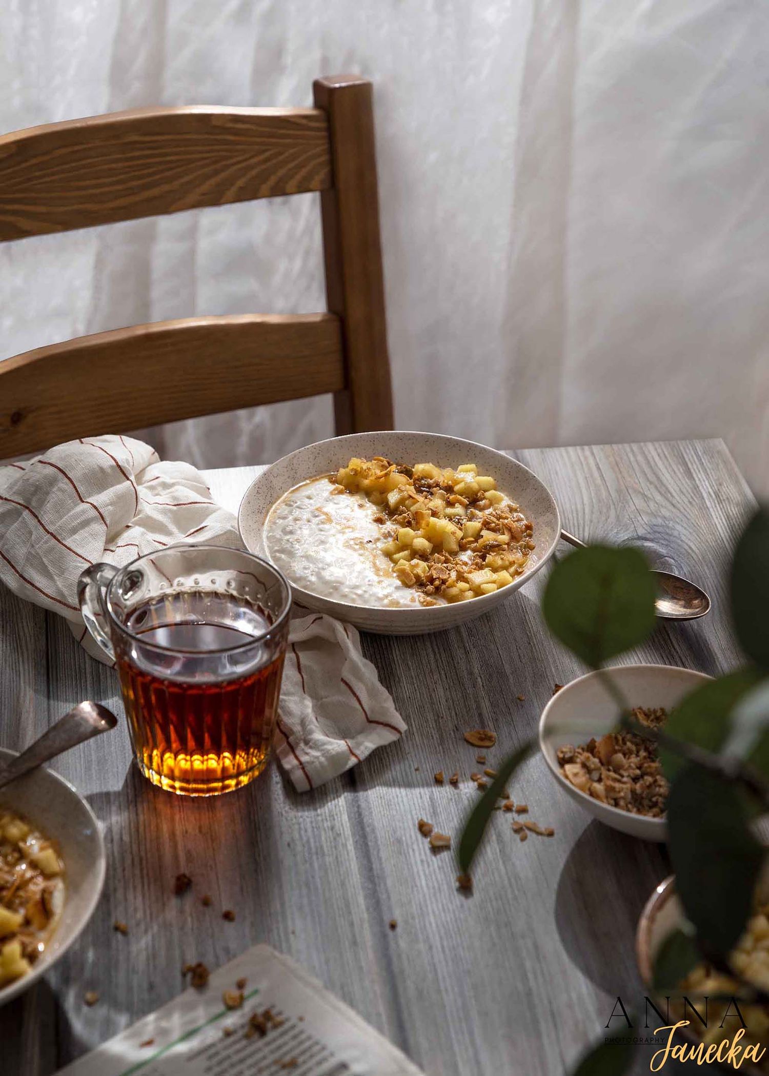 A warm tea service with pastries and desserts on a wooden table with white linens.