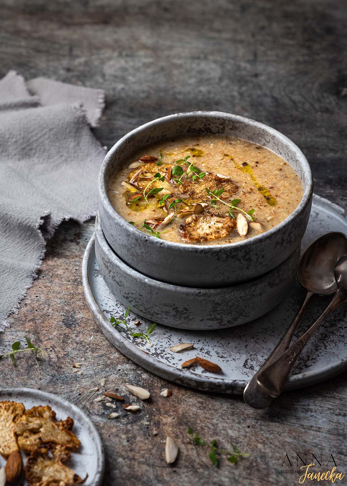 Creamy mushroom soup garnished with herbs served in a gray ceramic bowl.